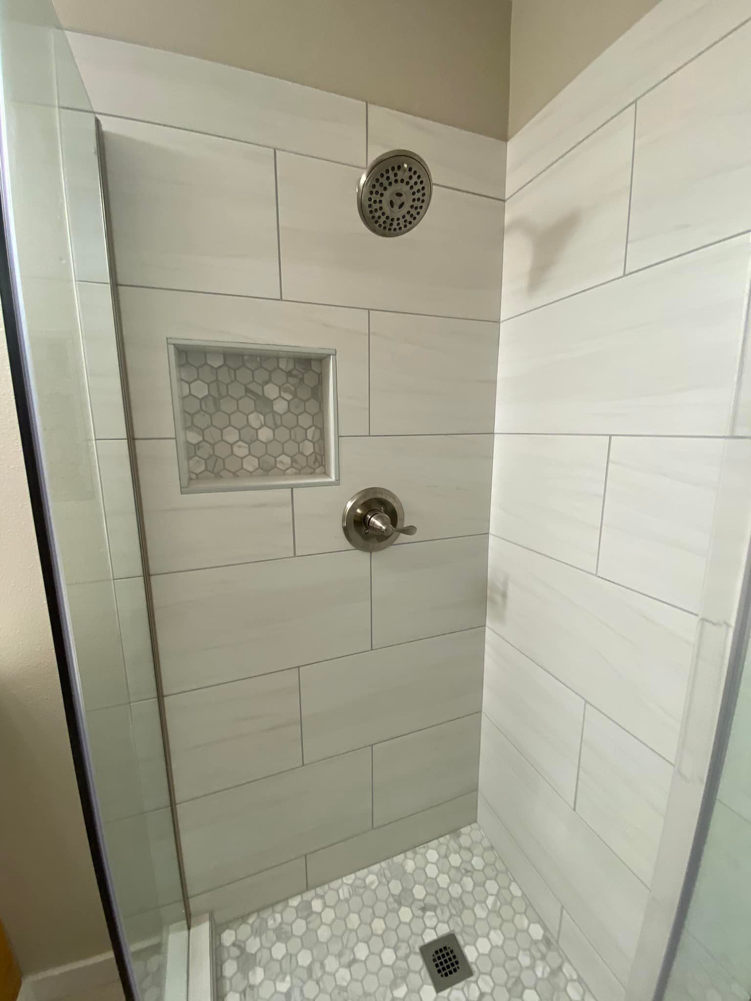 A walk in shower with a glass door and a shower head.