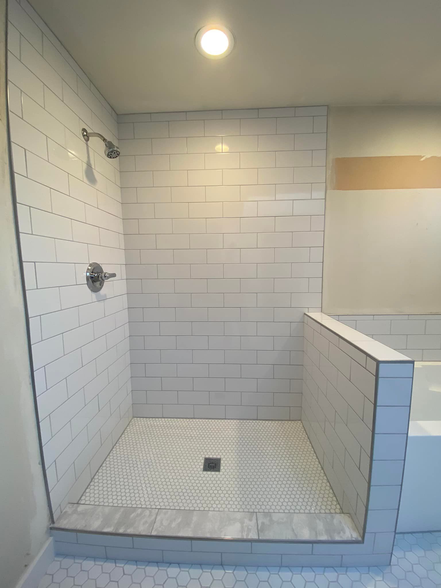 A bathroom with white tiles and a walk in shower
