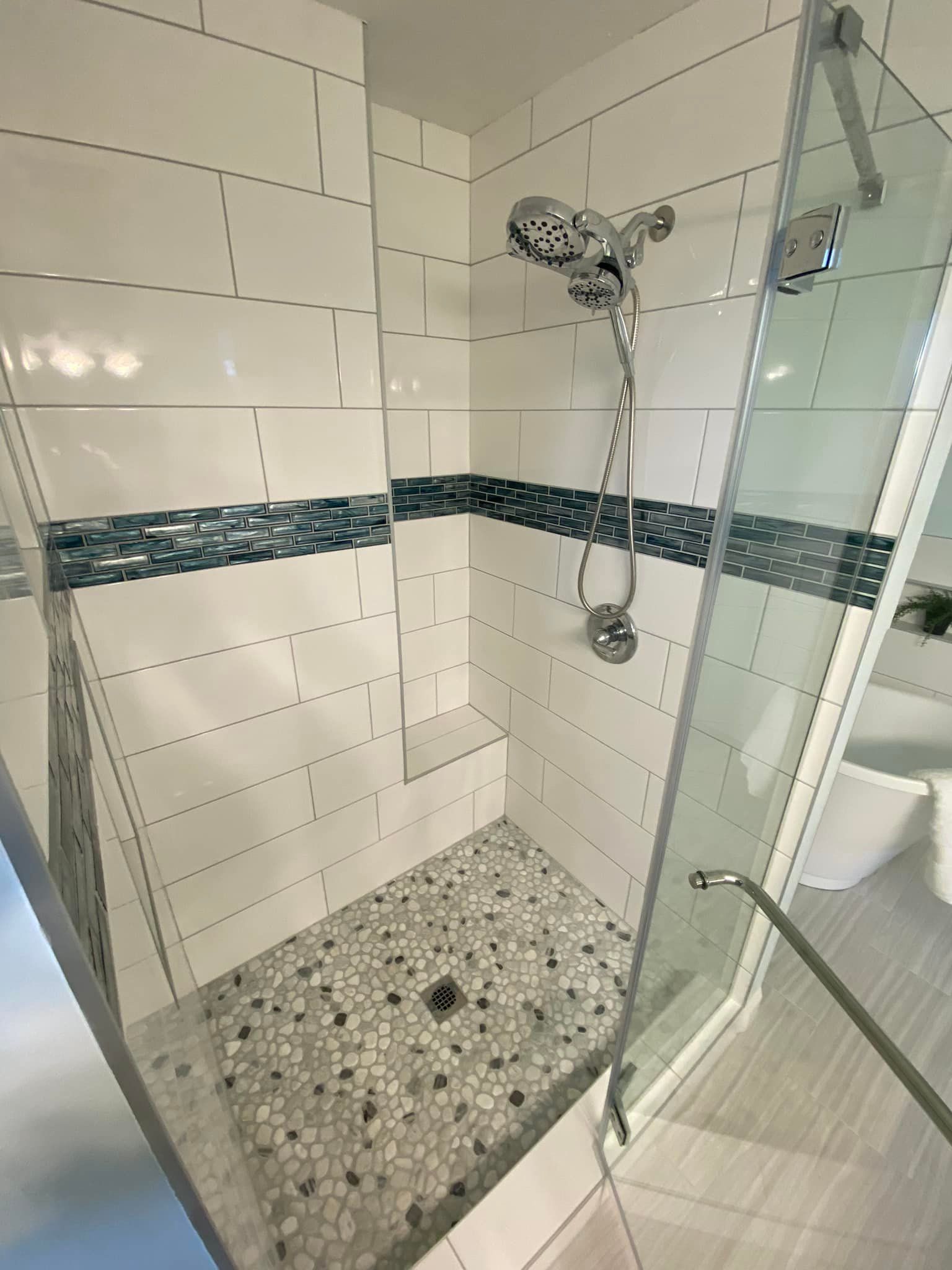A bathroom with a walk in shower with a glass door.