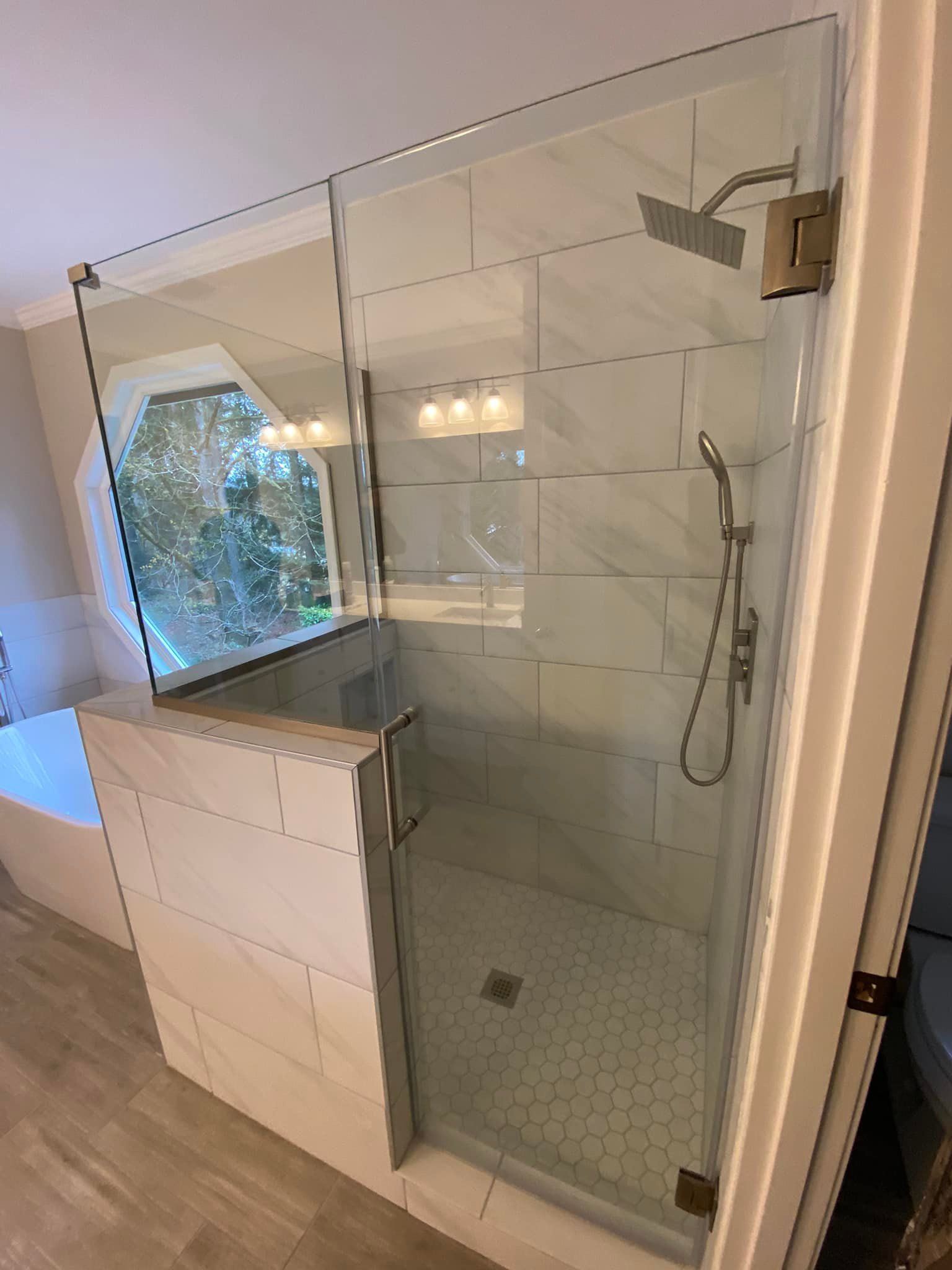 A bathroom with a walk in shower with a glass door.