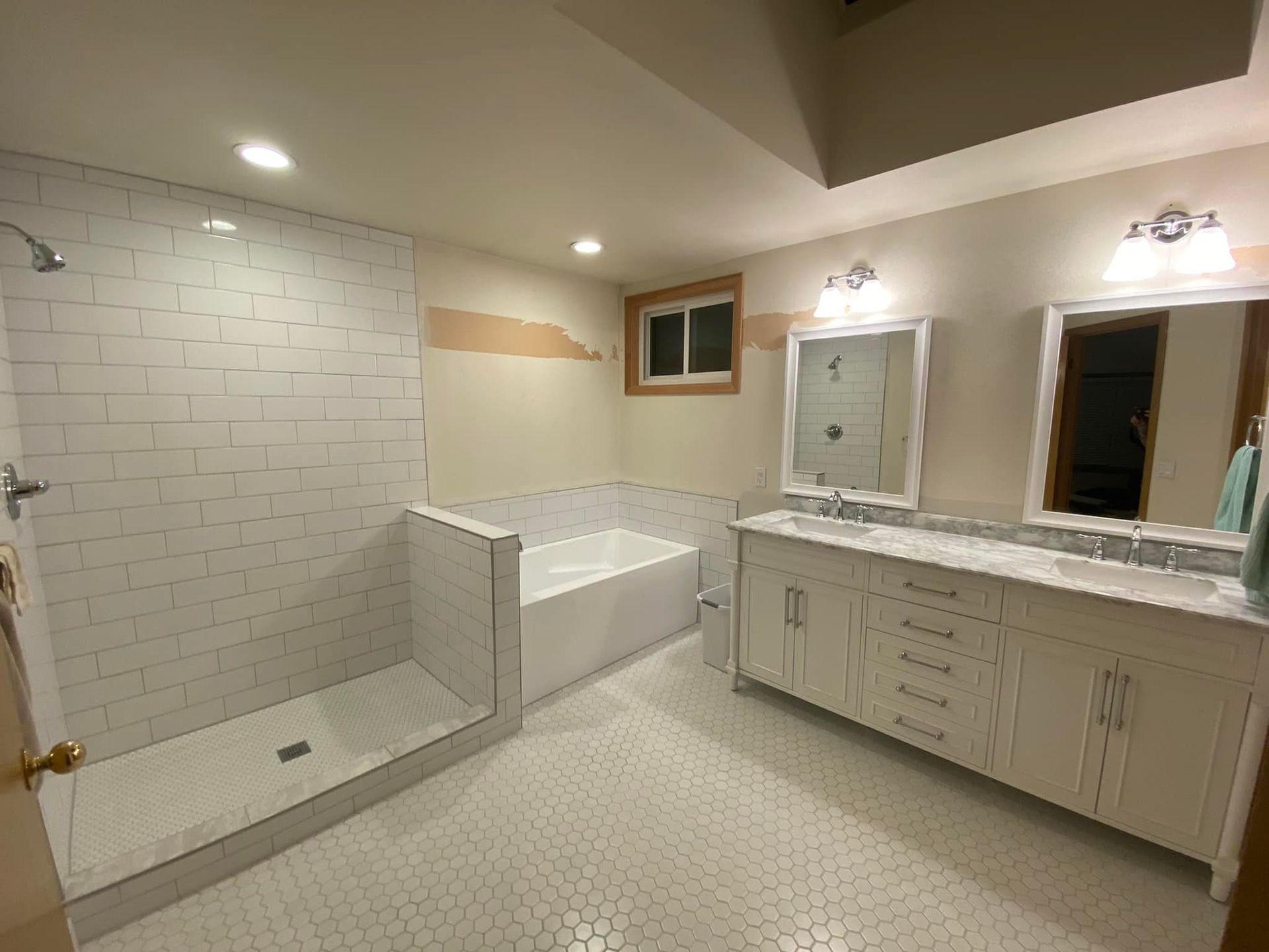 A bathroom with two sinks , a tub , and a walk in shower.