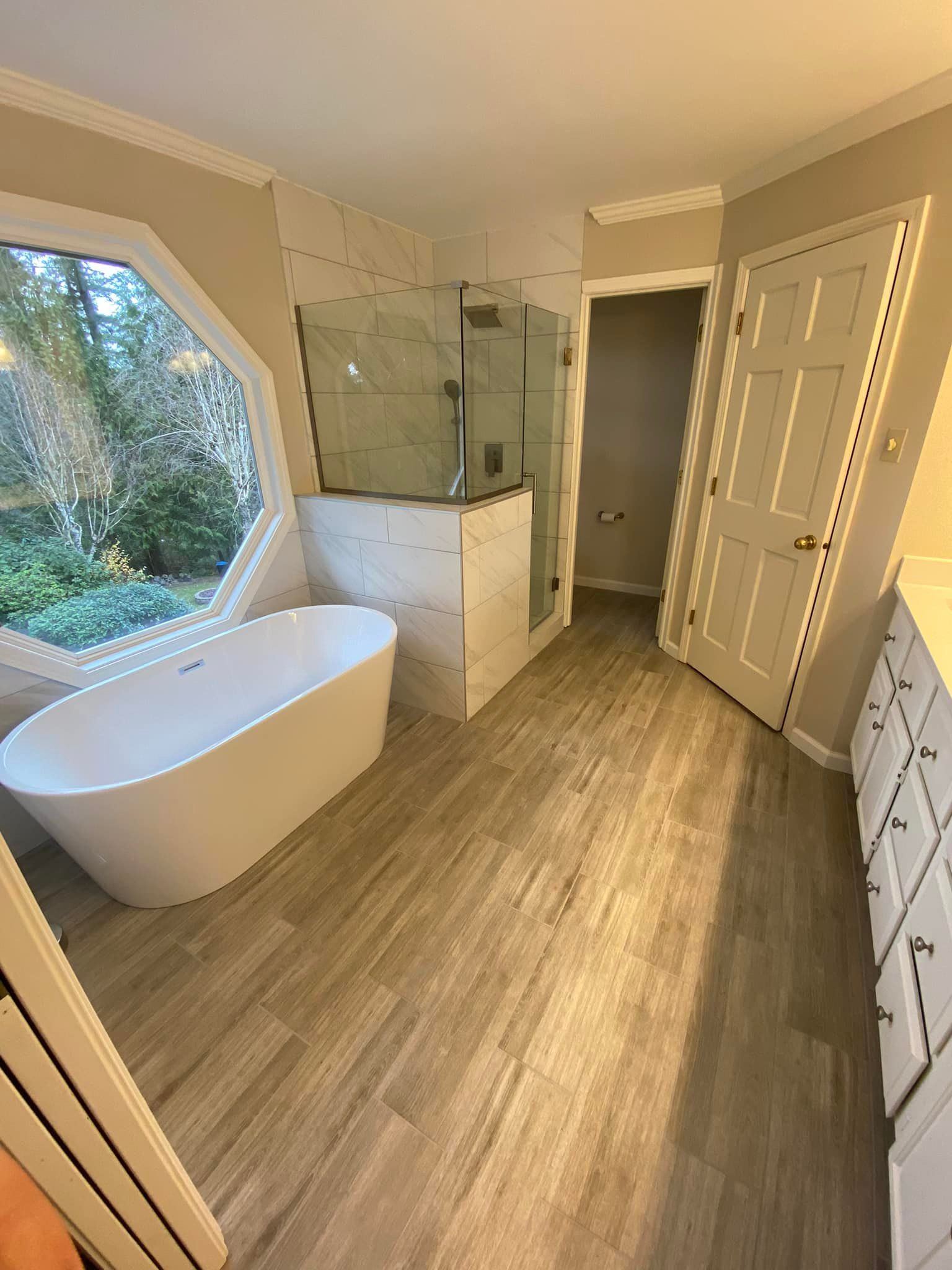 A bathroom with a tub , shower , and window.