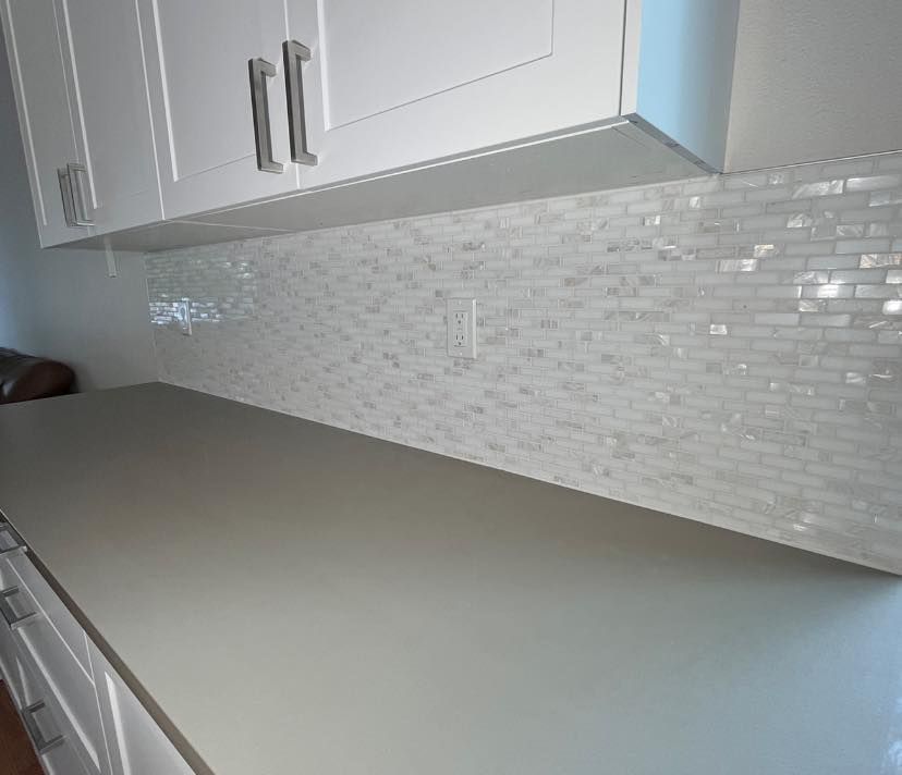 A kitchen with white cabinets and a white counter top.