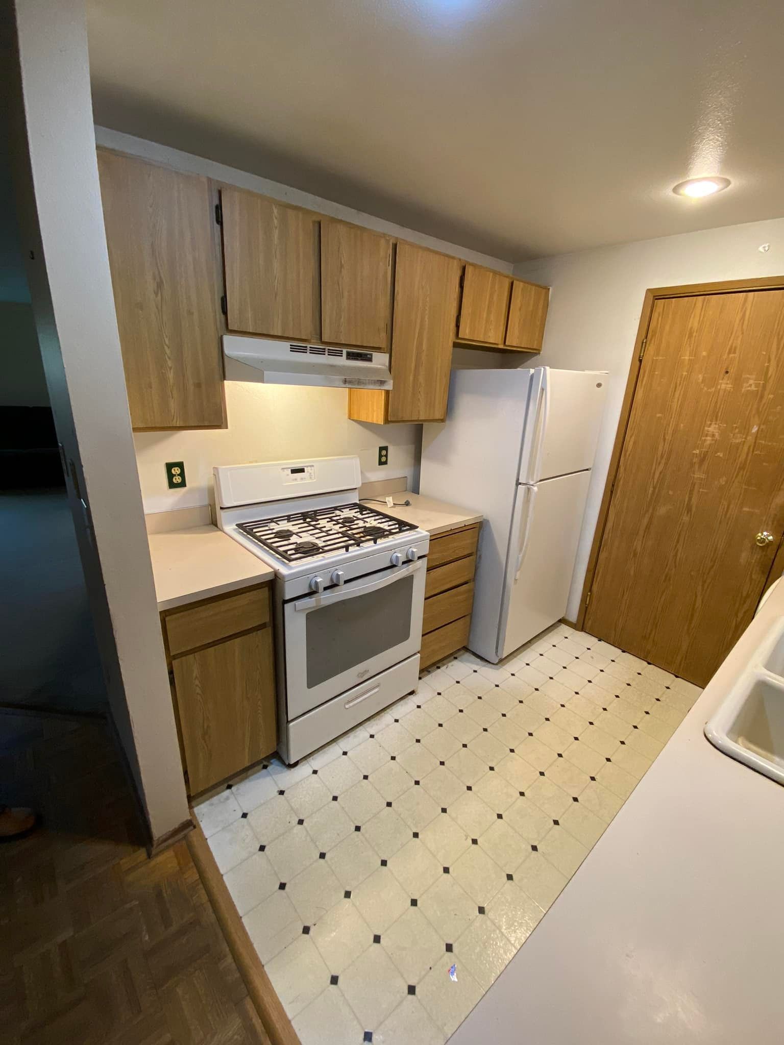 A kitchen with a stove , refrigerator , and sink.