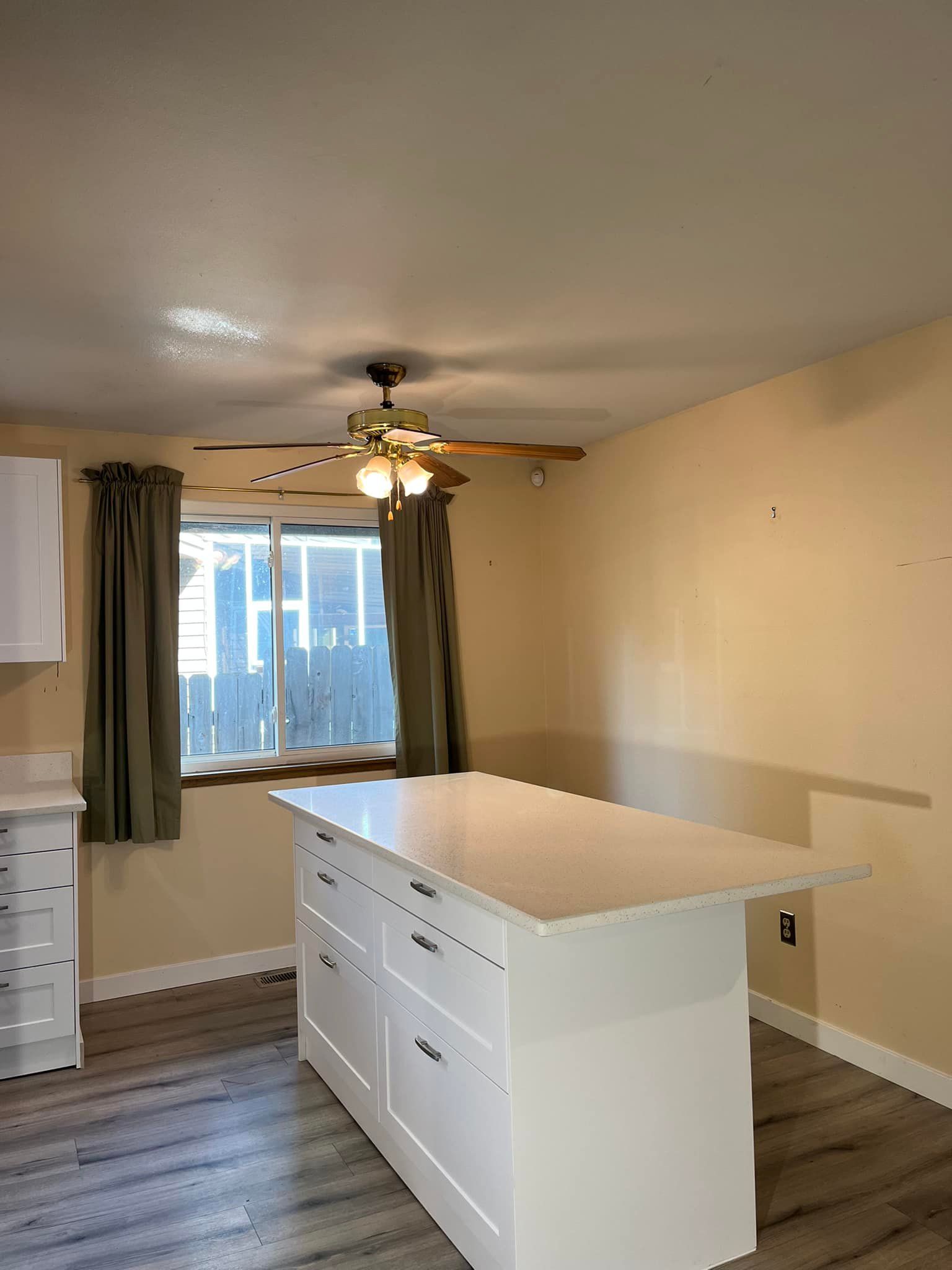 A kitchen with a large island and a ceiling fan.