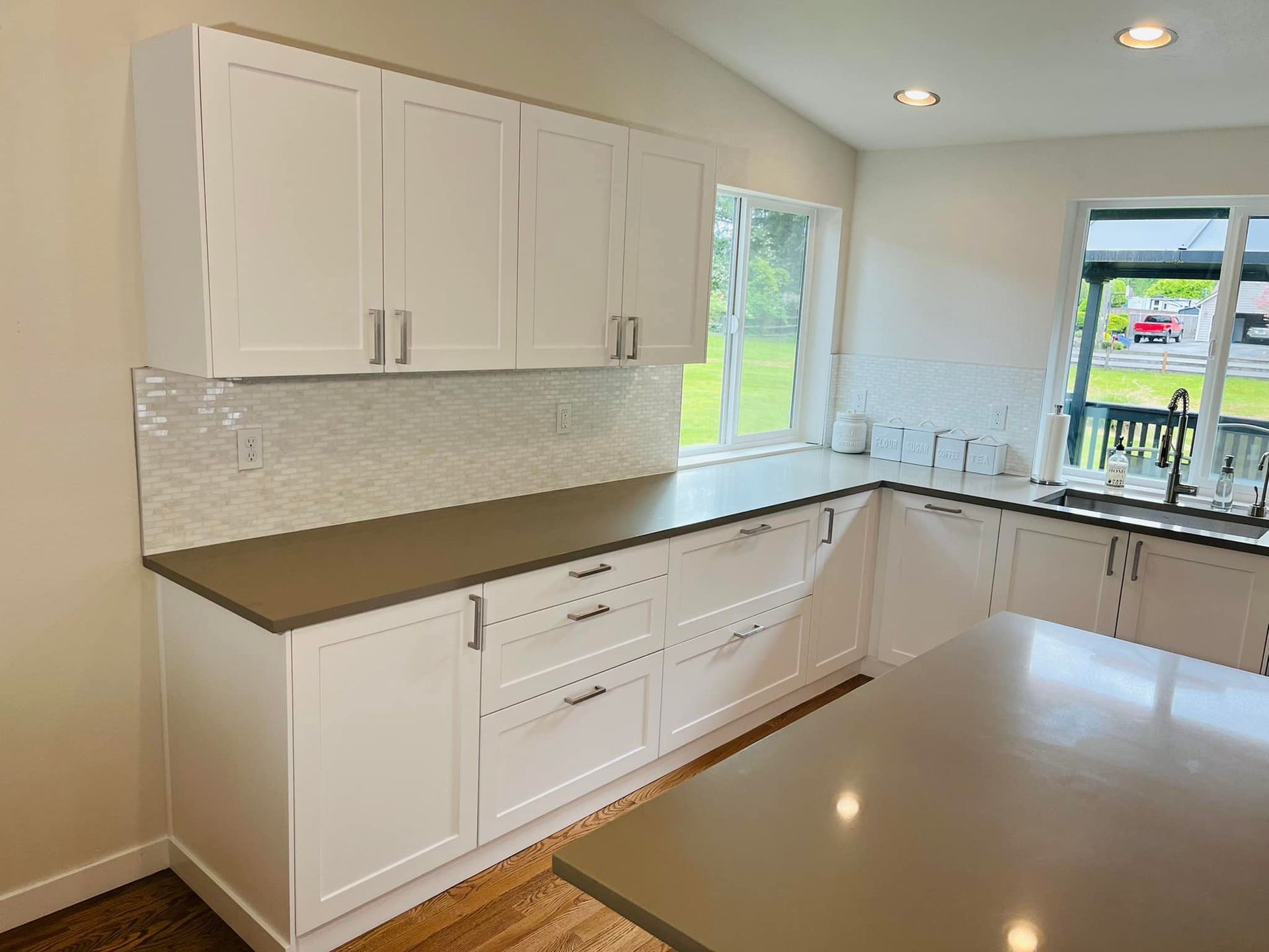 A kitchen with white cabinets , granite counter tops , and a large island.