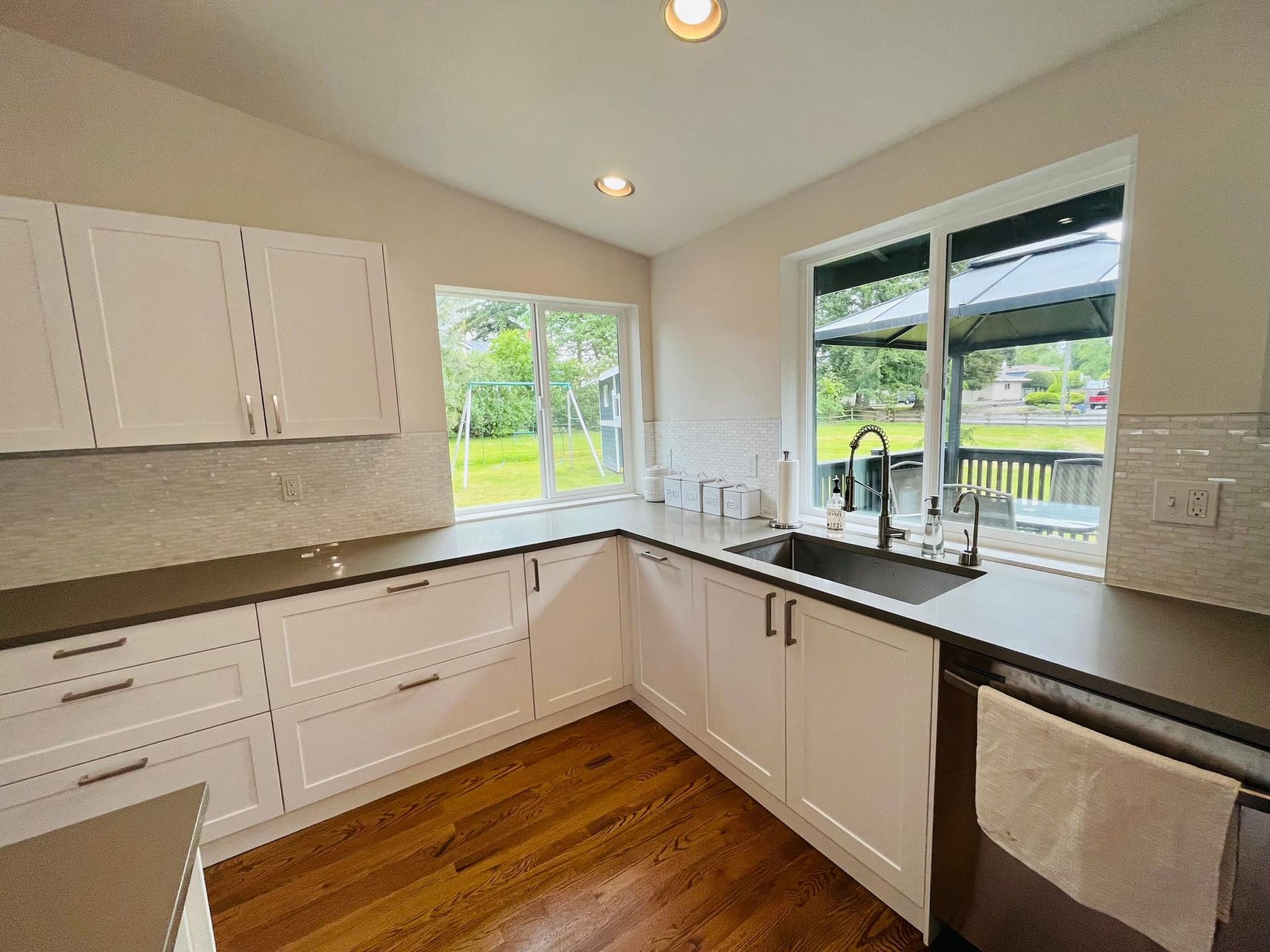 A kitchen with white cabinets , a sink , and a window.