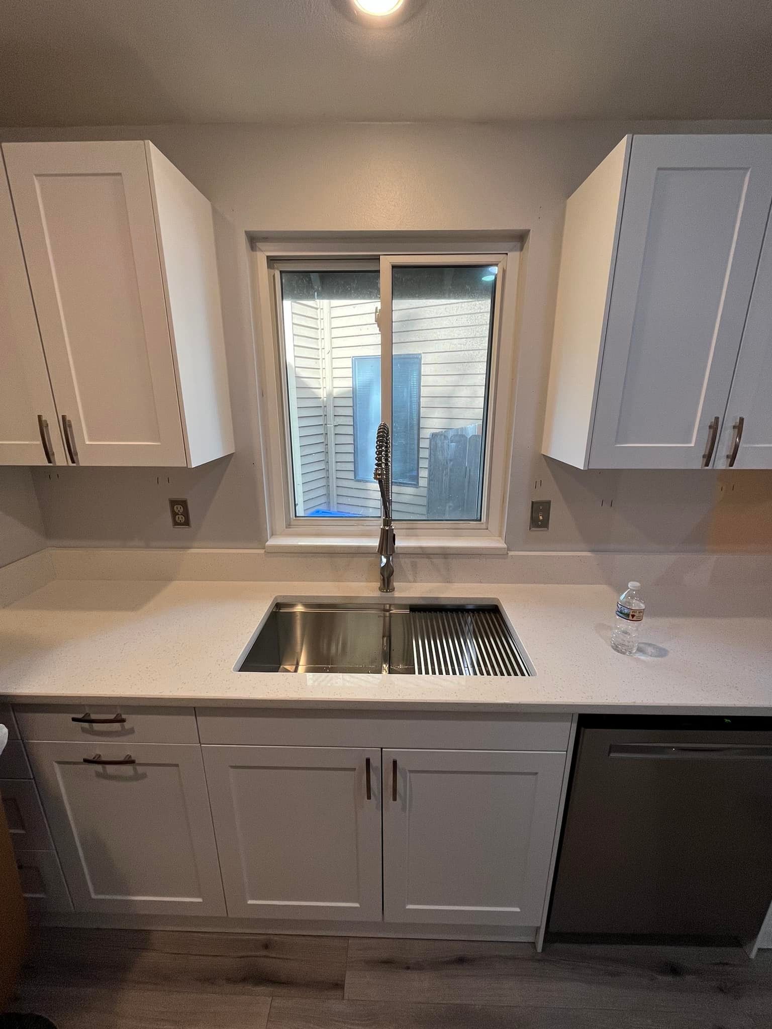 A kitchen with white cabinets and a stainless steel sink