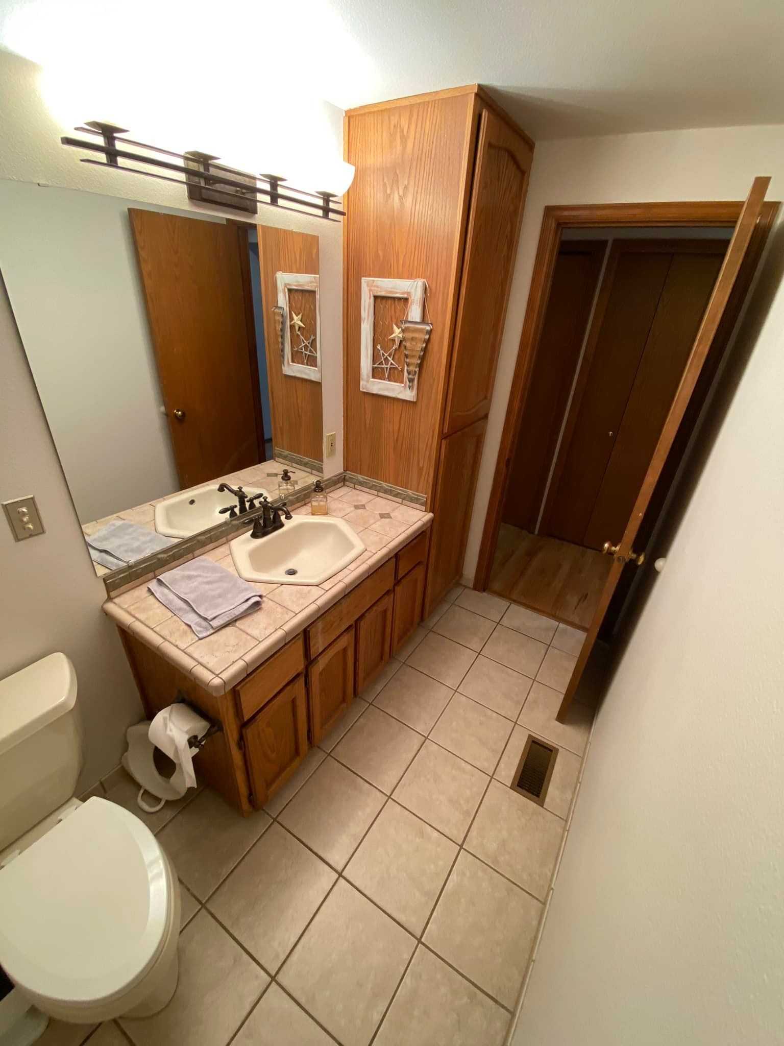 A bathroom with a toilet , sink and mirror.