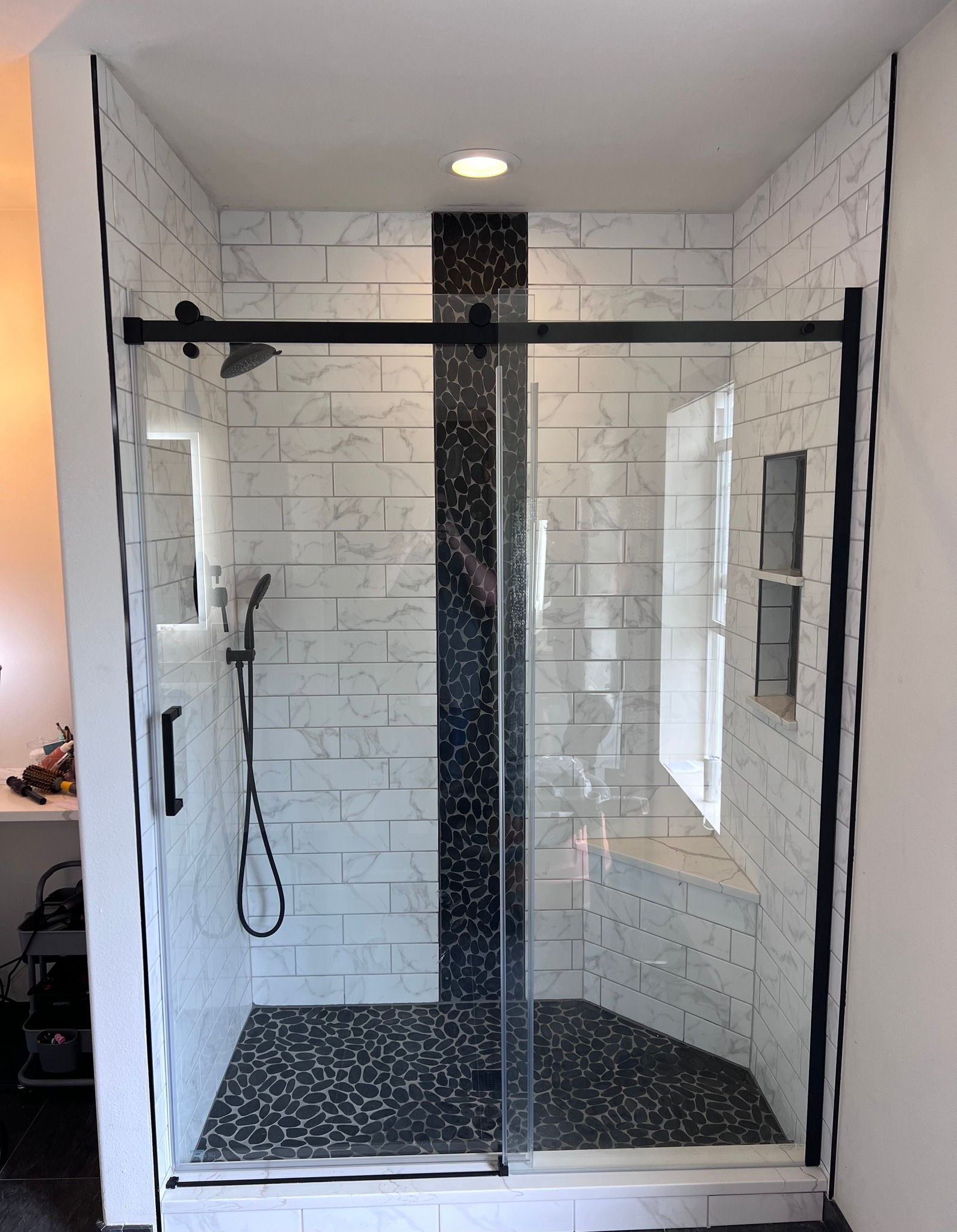 A bathroom with a sliding glass shower door and white tiles.