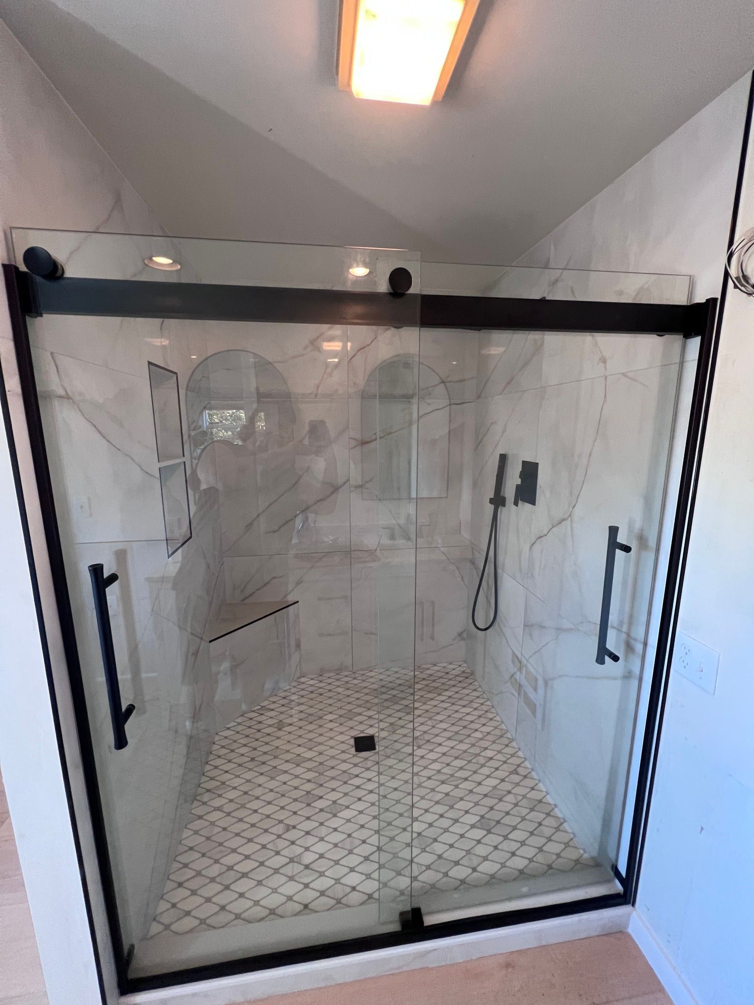 A bathroom with a walk in shower with a sliding glass door.