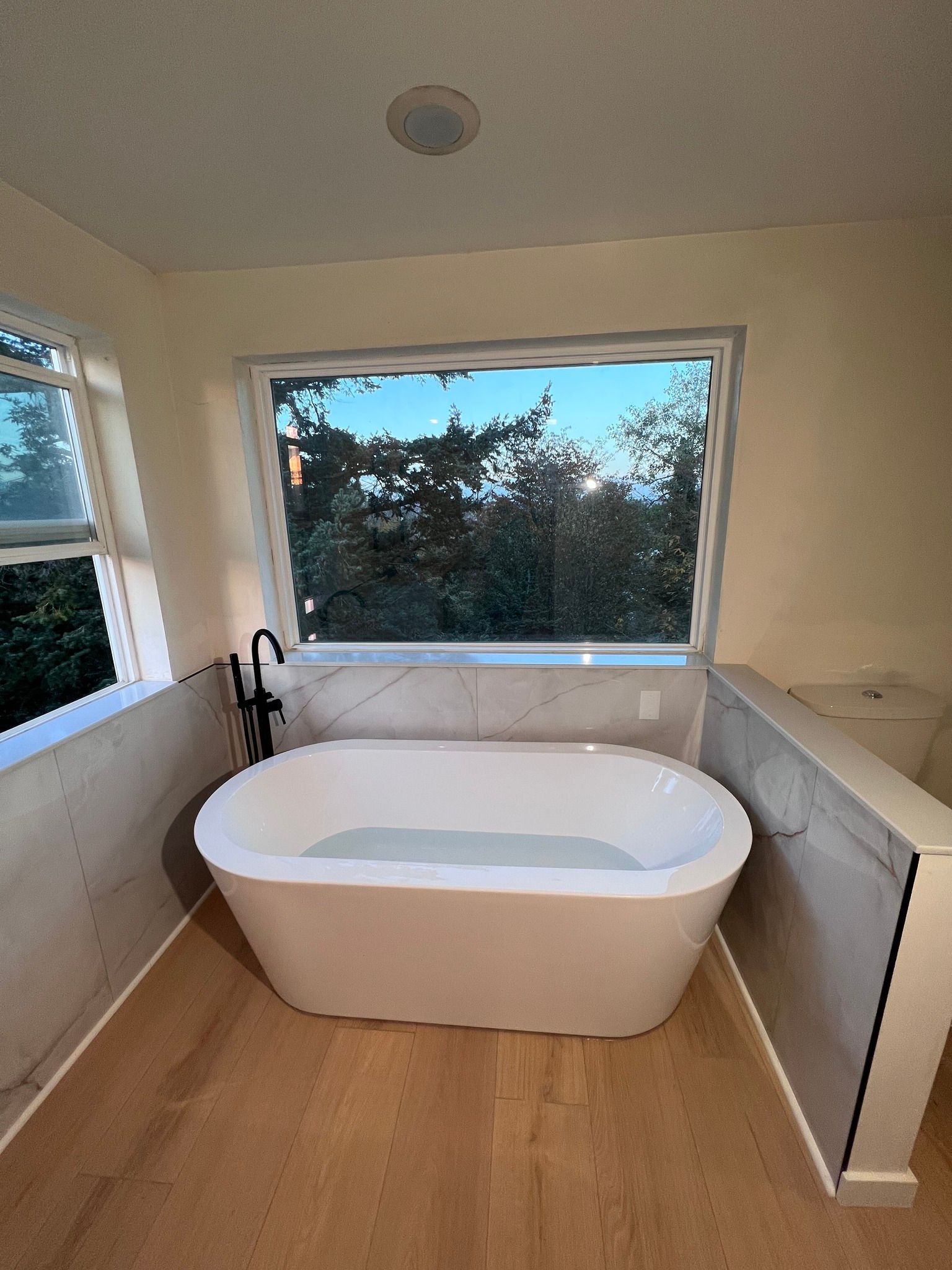 A bathtub in a bathroom next to a window.