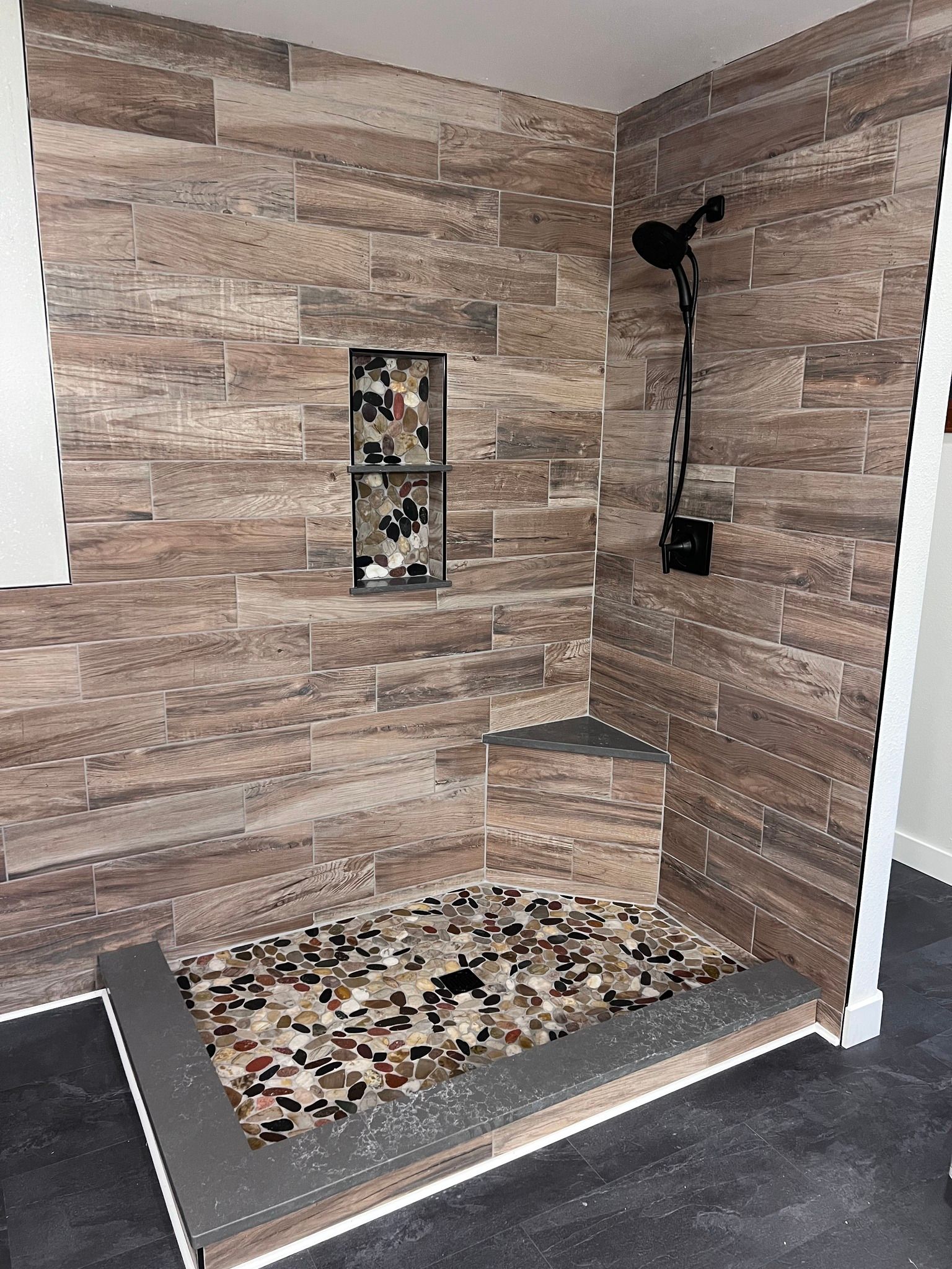 A bathroom with a walk in shower and a brick wall.