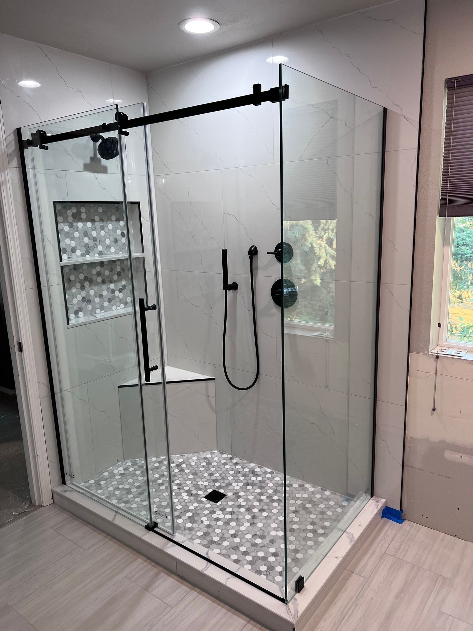 A bathroom with a sliding glass shower door and a window.