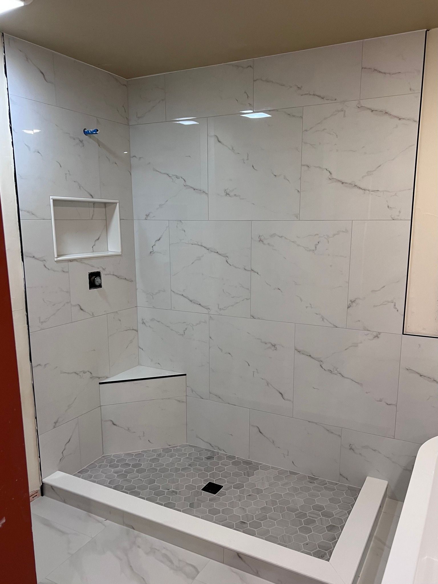 A bathroom with white tiles and a walk in shower.
