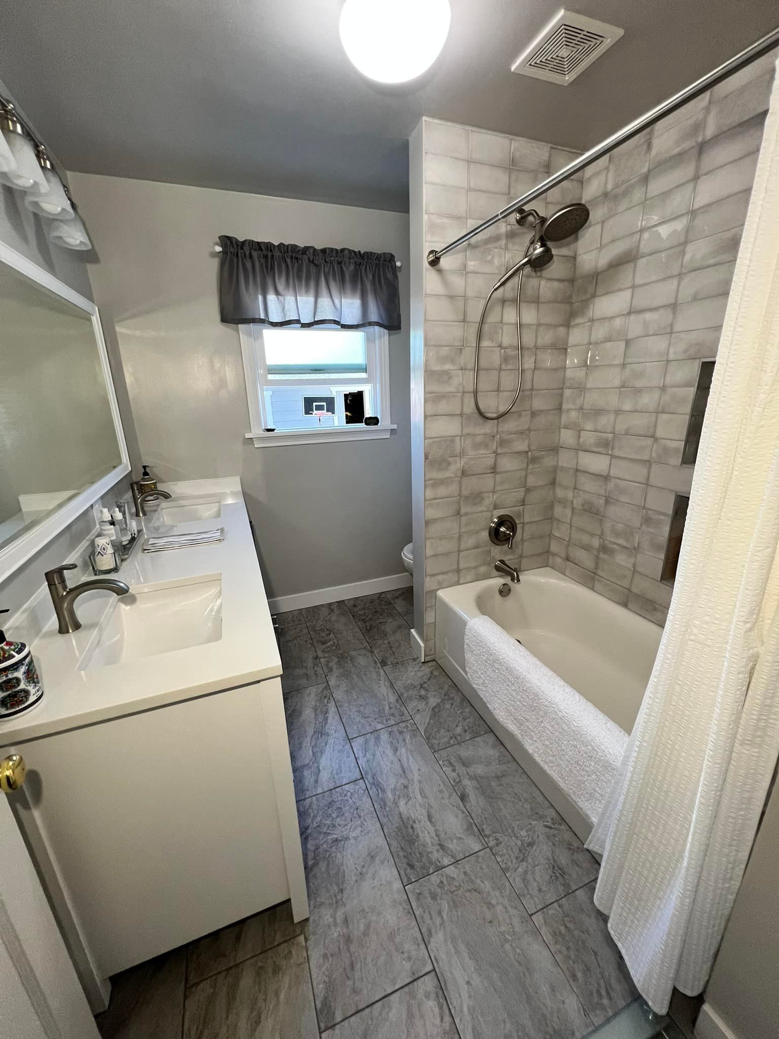 A bathroom with a tub , sink , mirror and shower.