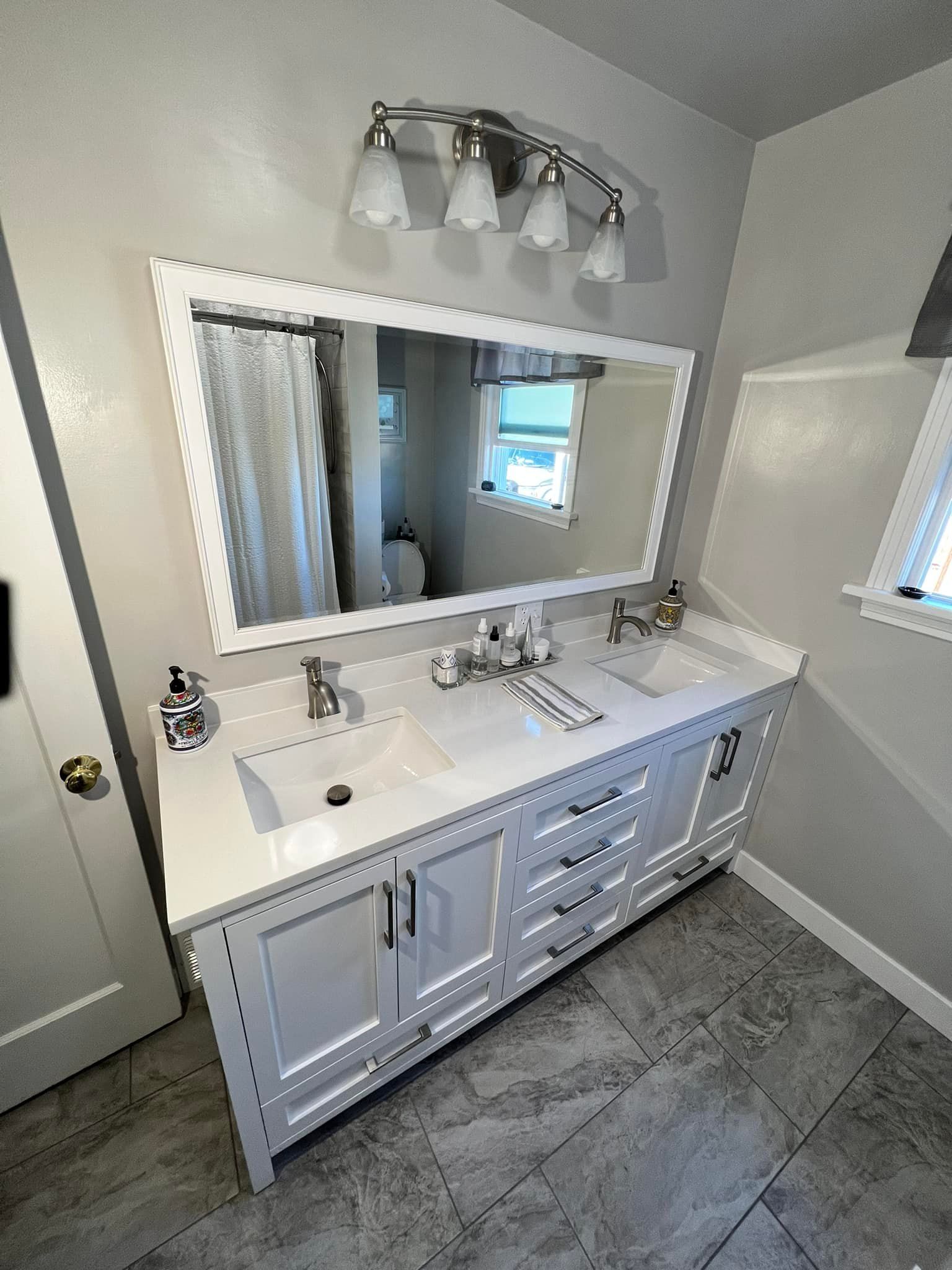 A bathroom with two sinks and a large mirror.