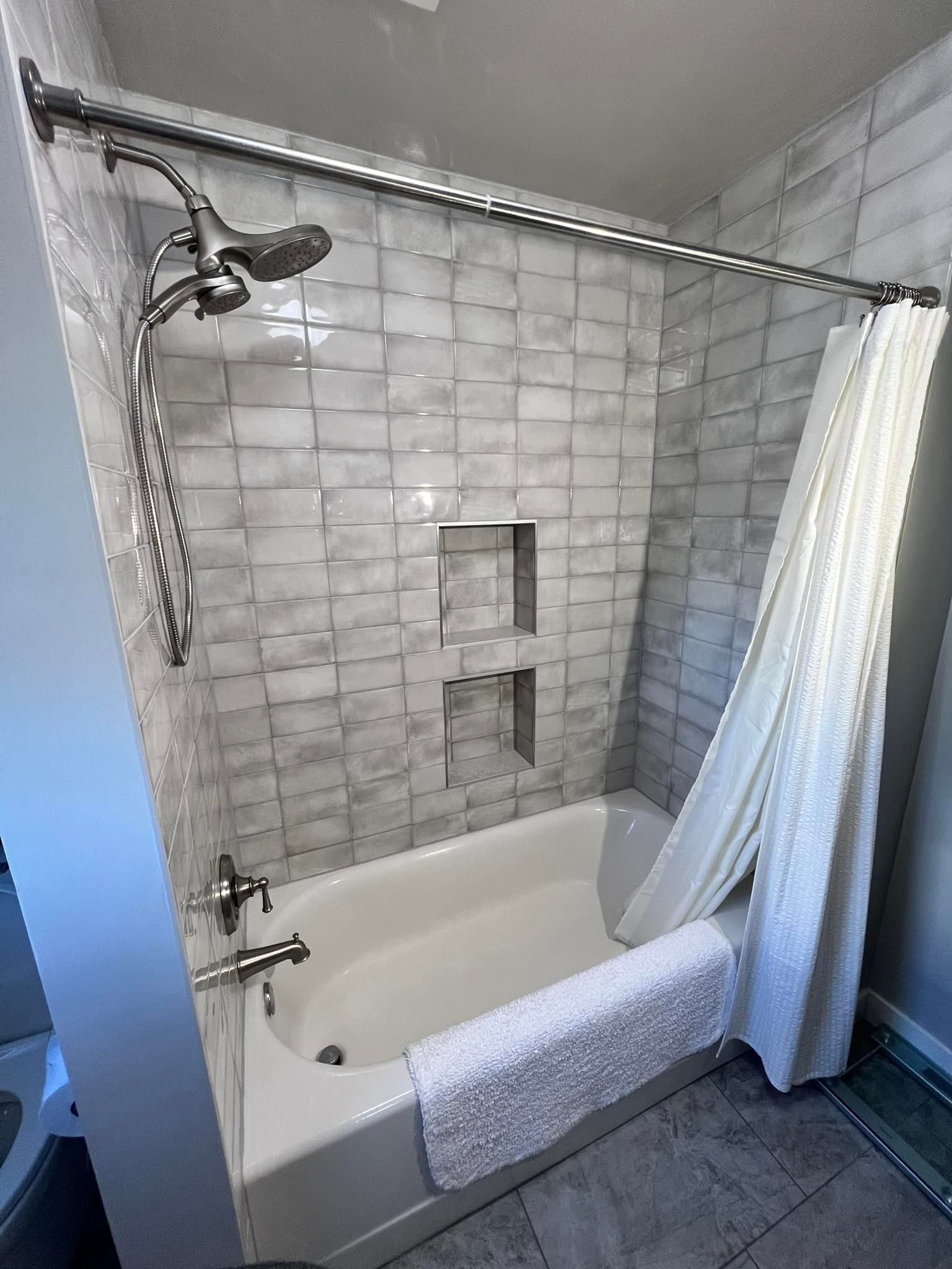 A bathroom with a bathtub , shower , and towels.