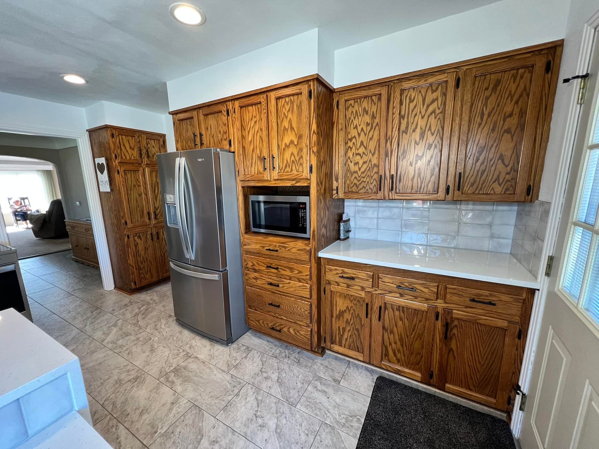 A kitchen with wooden cabinets and a stainless steel refrigerator.