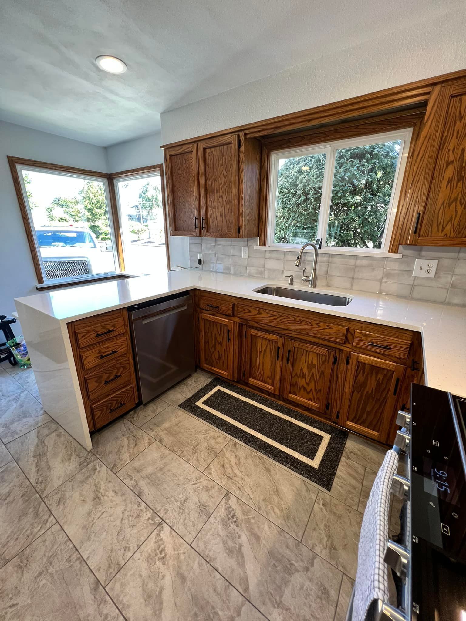 A kitchen with wooden cabinets , white counter tops , a sink , and a stove.
