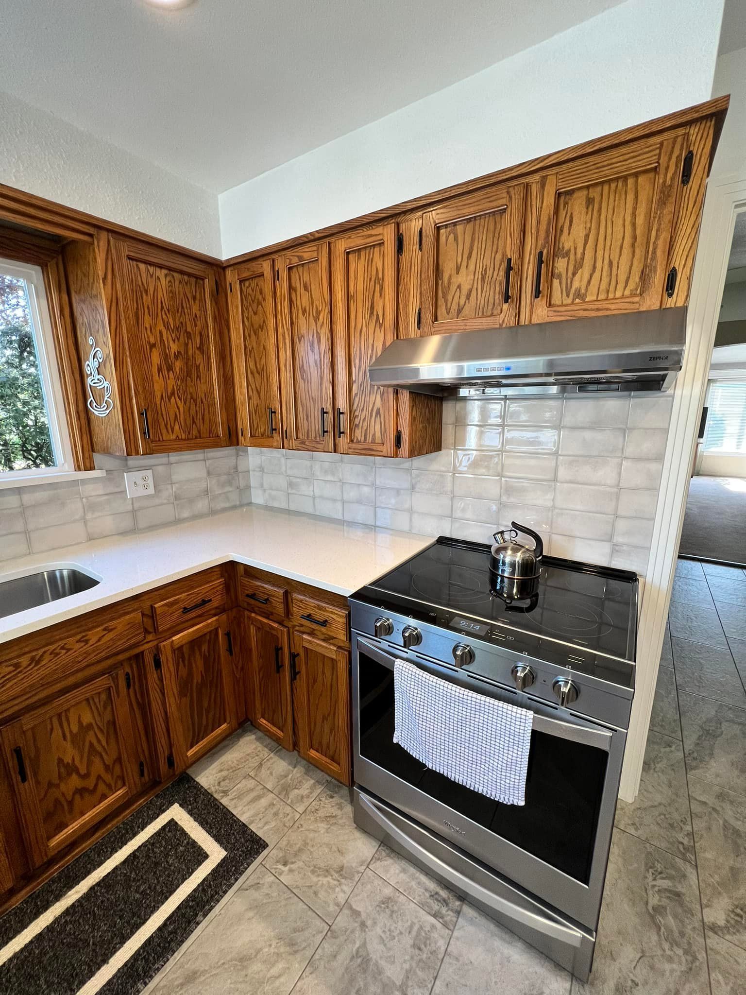 A kitchen with wooden cabinets , a stove and a sink.