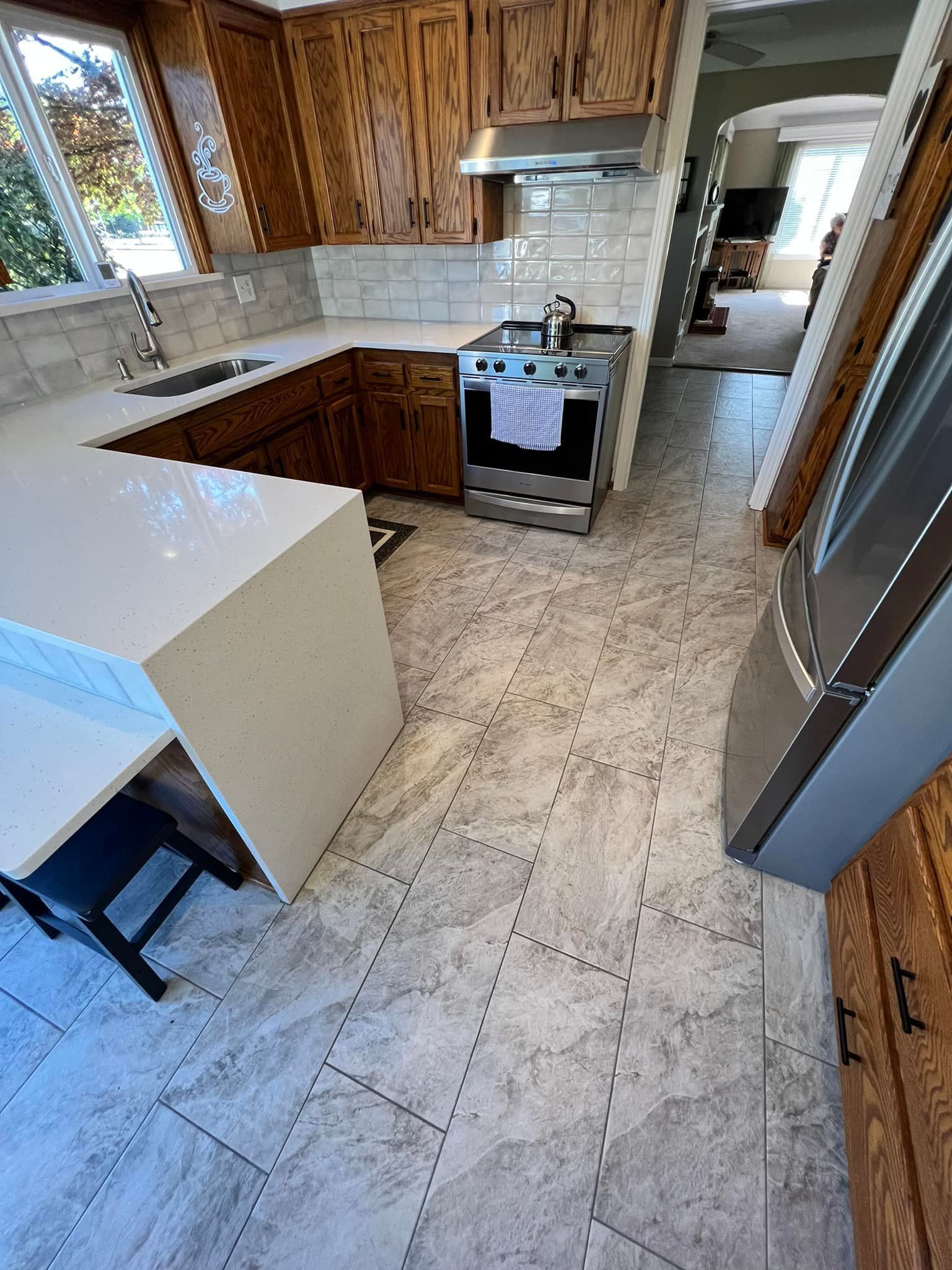 A kitchen with a stove , refrigerator , sink , and wooden cabinets.