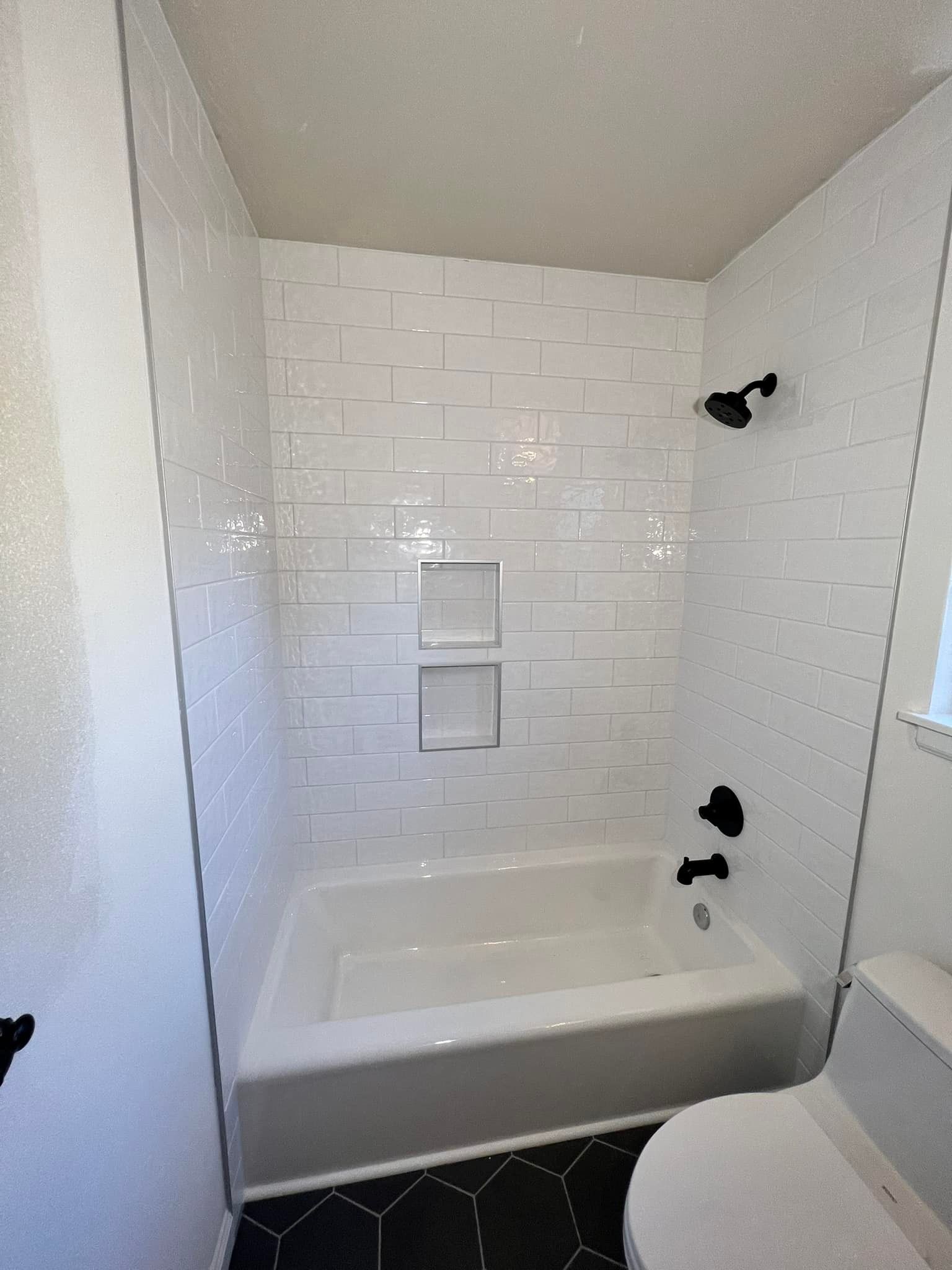 A bathroom with a bathtub , toilet and shower.