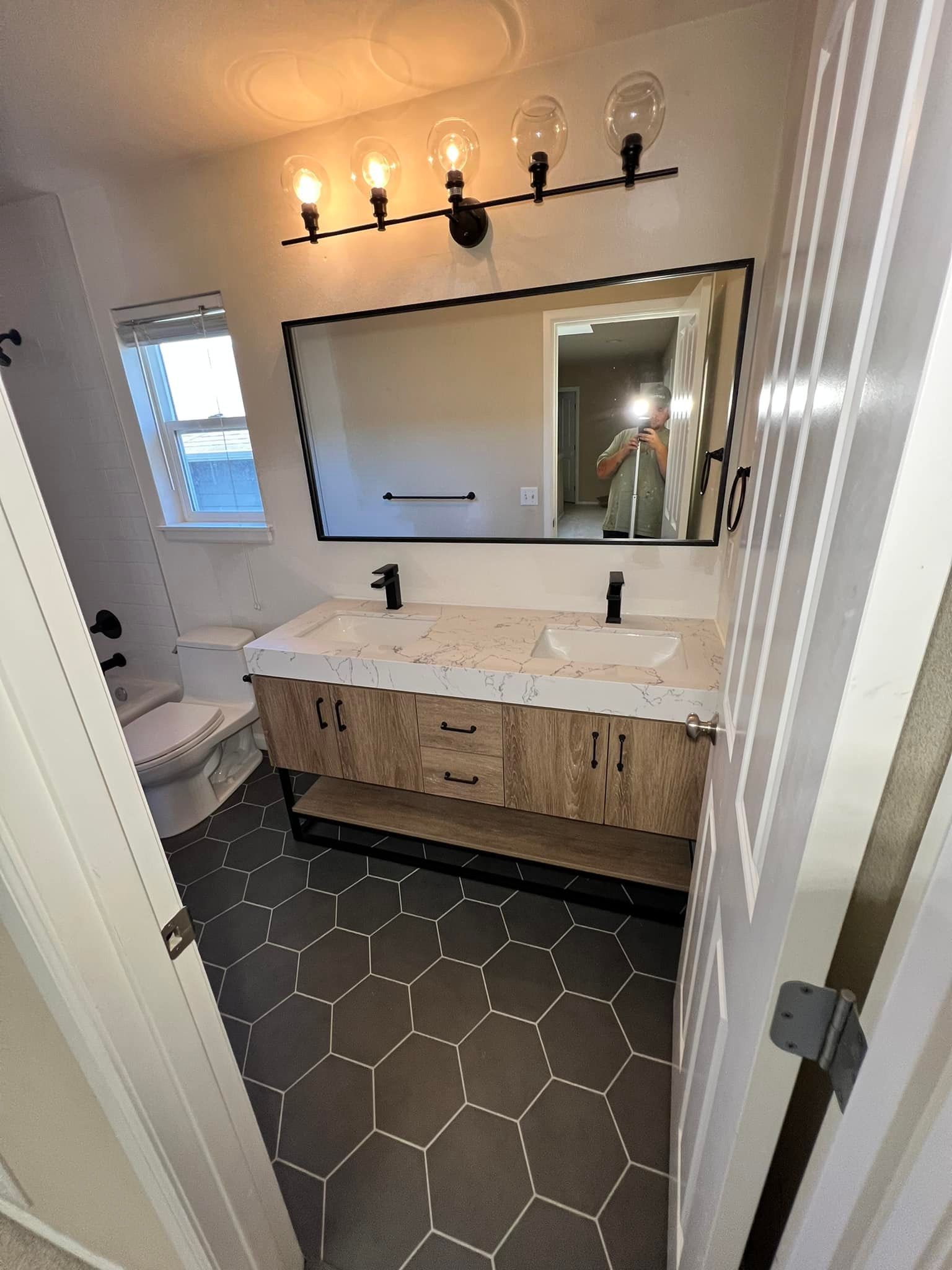 A bathroom with two sinks , a toilet and a mirror.