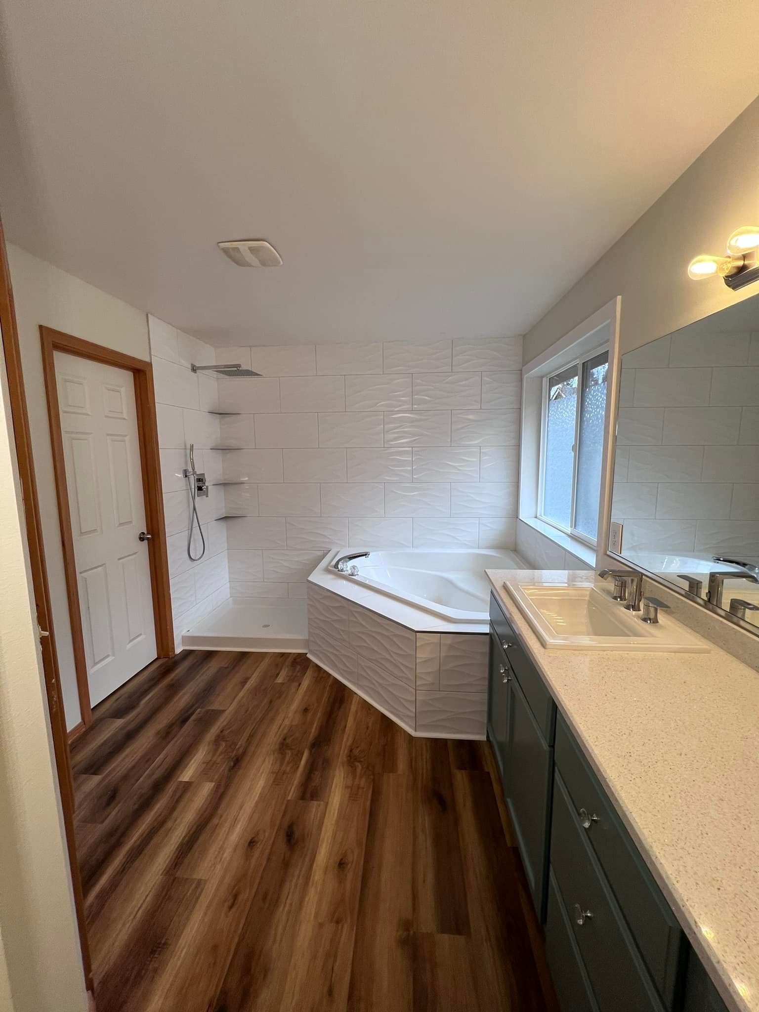 A bathroom with a tub , sink , and mirror.