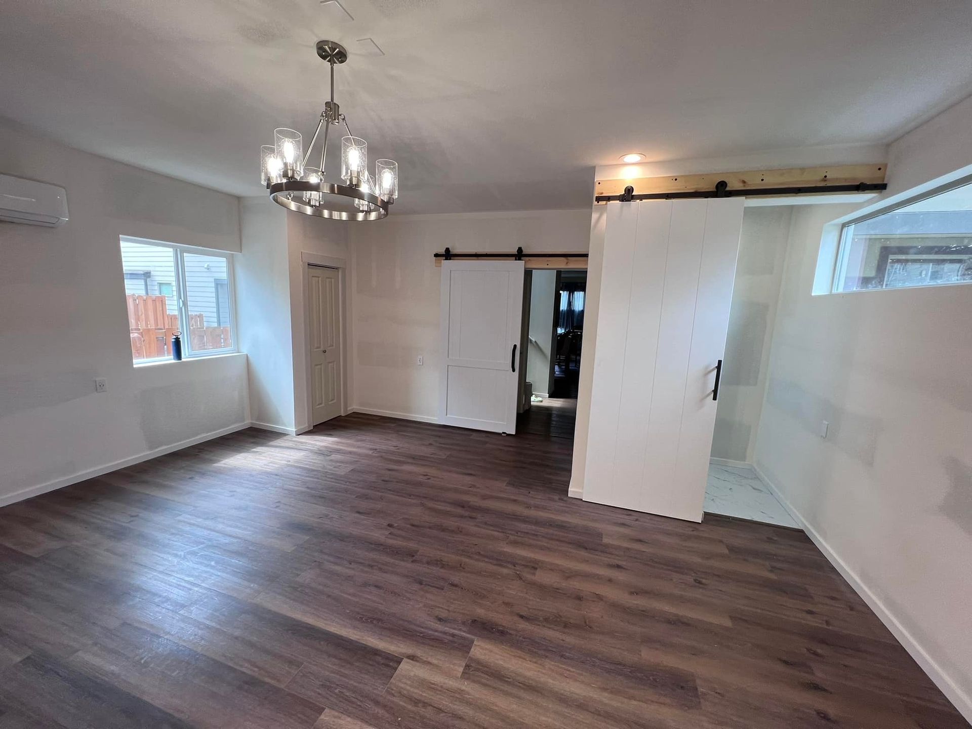 An empty living room with hardwood floors and a chandelier.
