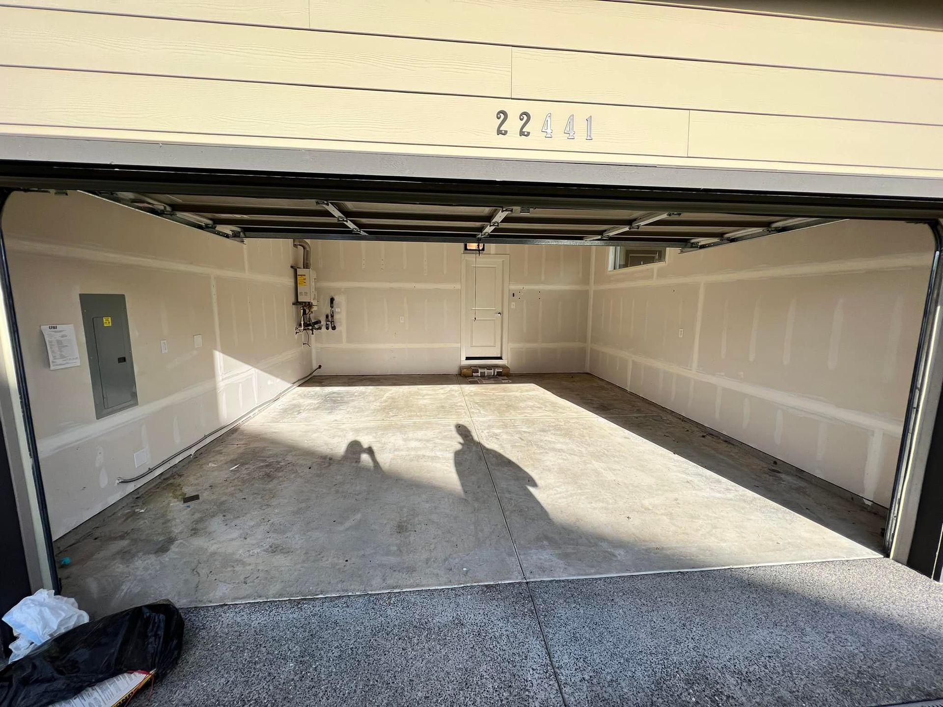 A garage with a door open and a shadow on the ground.