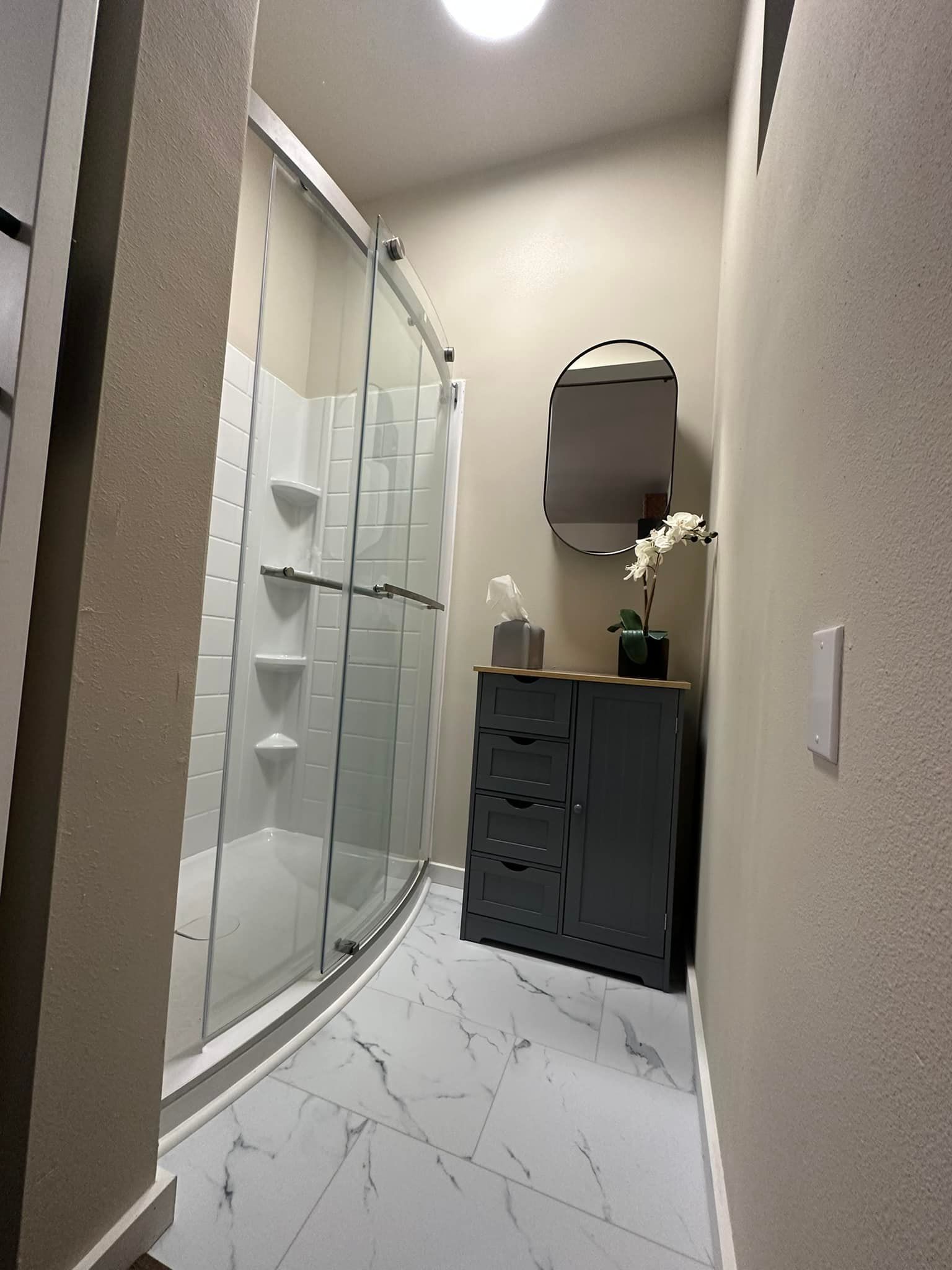 A bathroom with a walk in shower and a dresser.