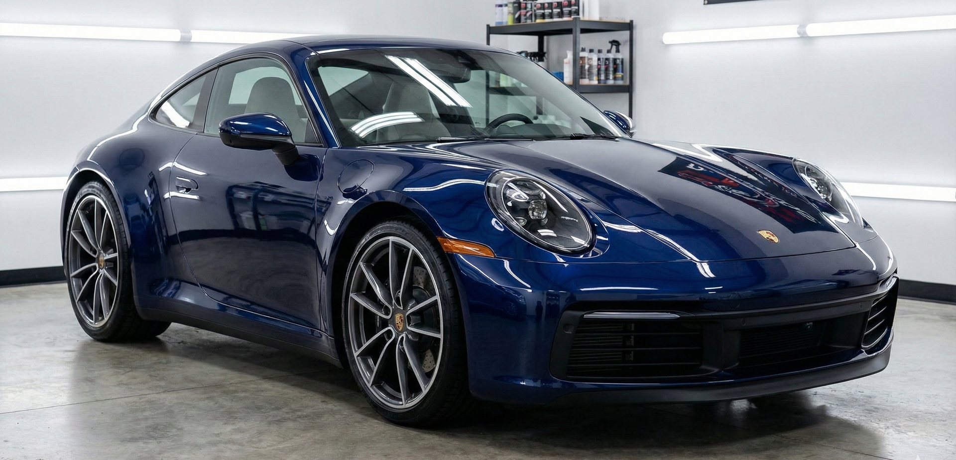 A shiny blue Porsche coupe in a well-lit showroom.