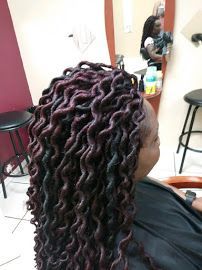A woman with dreadlocks is sitting in a chair in front of a mirror.