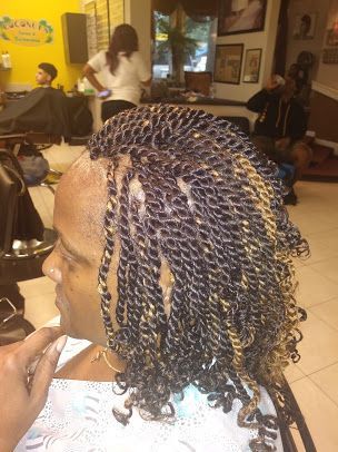 A woman is getting her hair braided in a salon.