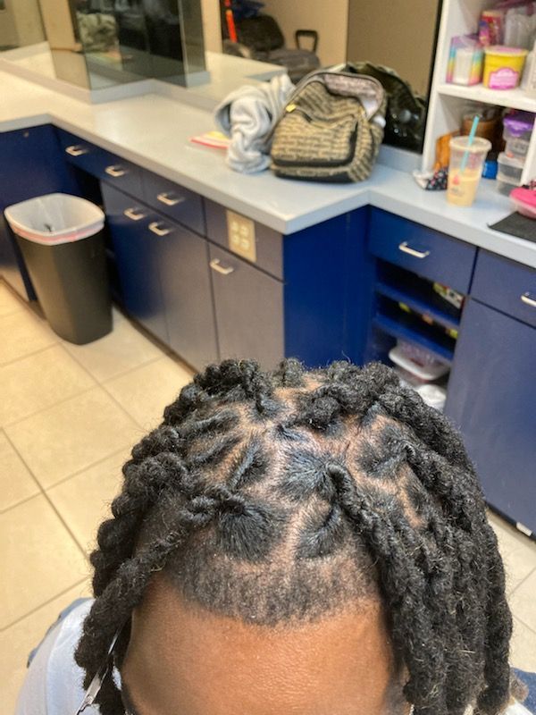 A person with dreadlocks is sitting in front of a counter