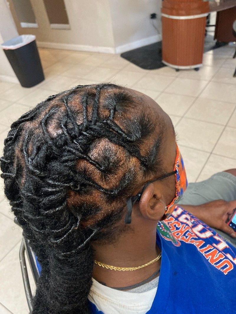 A woman with dreadlocks is sitting in a chair in a salon.