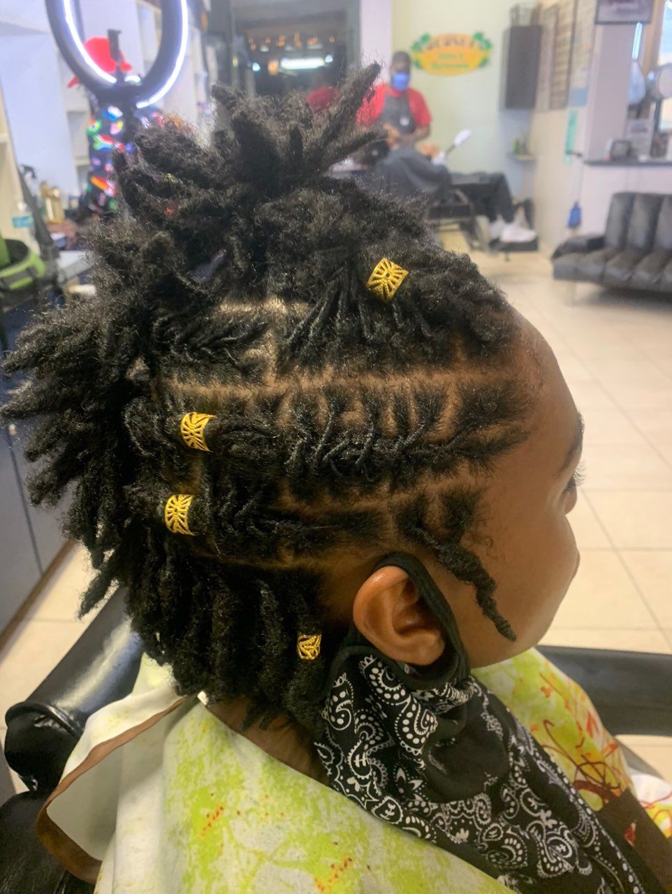 A little girl with dreadlocks is sitting in a chair in a salon.