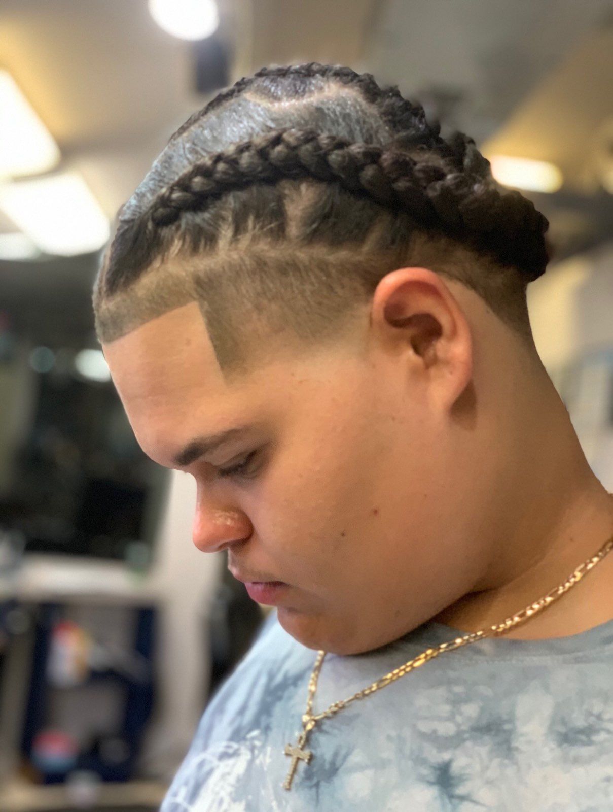 A young man with a braided hairstyle and a shaved head.
