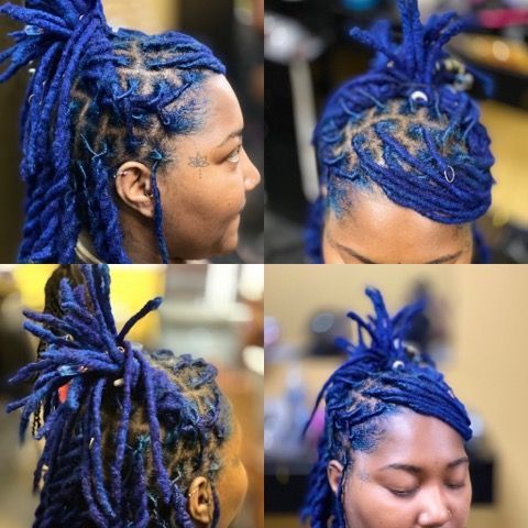 A woman with blue dreadlocks has a tattoo on her face