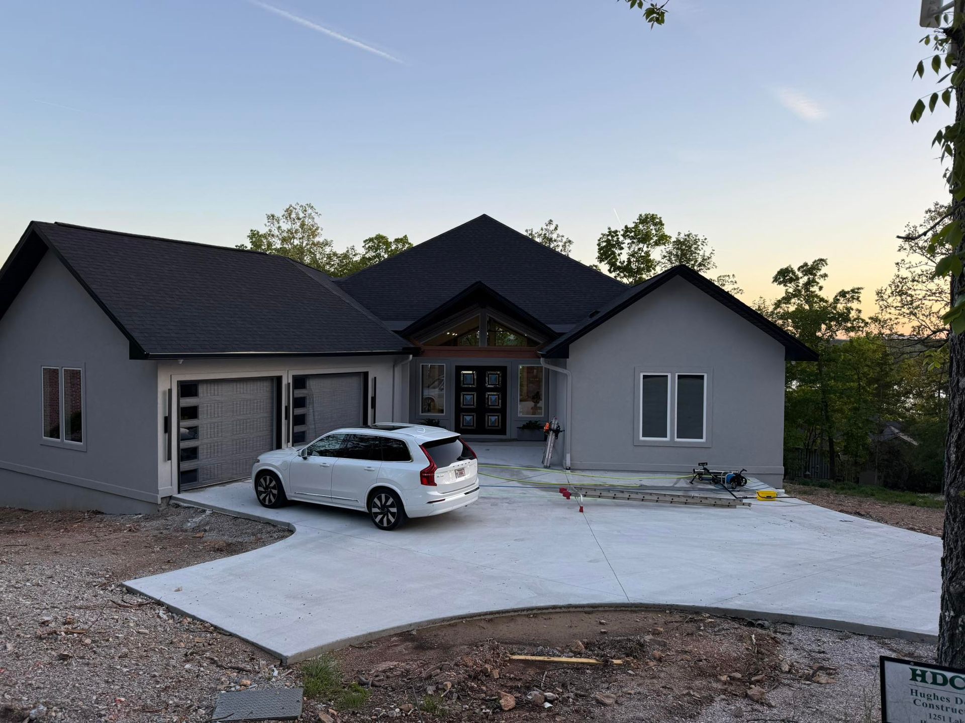 Modern single-story house with gray siding, a white SUV in the driveway, at dusk