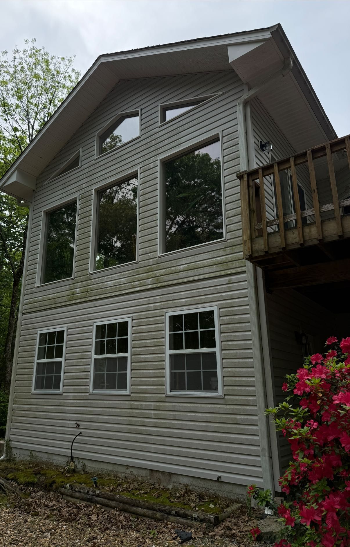Small weathered white house with a turquoise porch and attached garage, surrounded by trees.