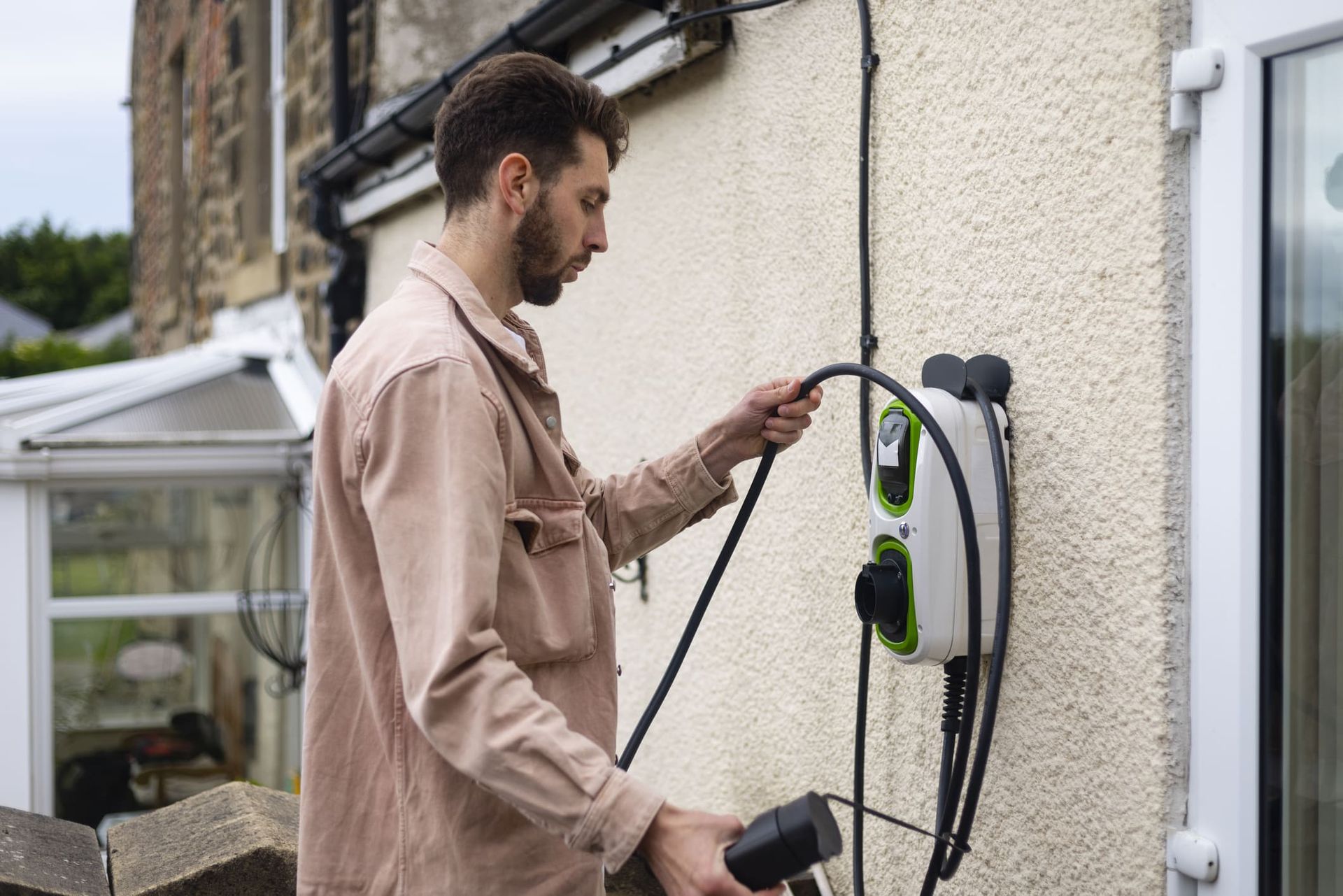 Young male adult unravelling wire on charging station