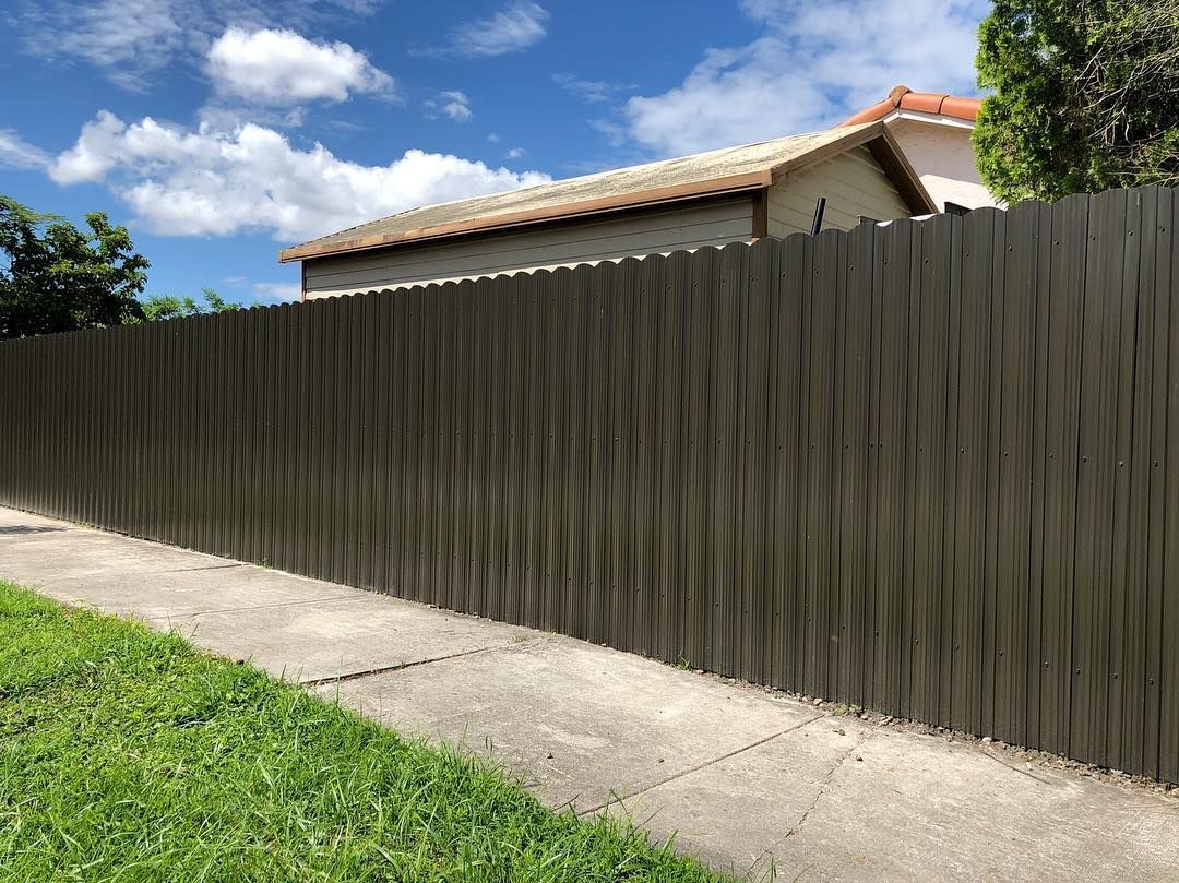 A wooden fence along a sidewalk next to a house.