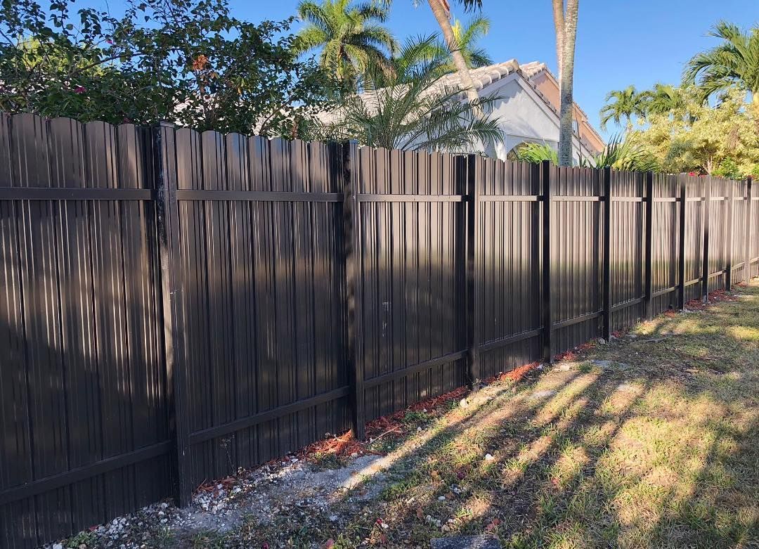 A wooden fence is surrounded by grass and trees in a backyard.