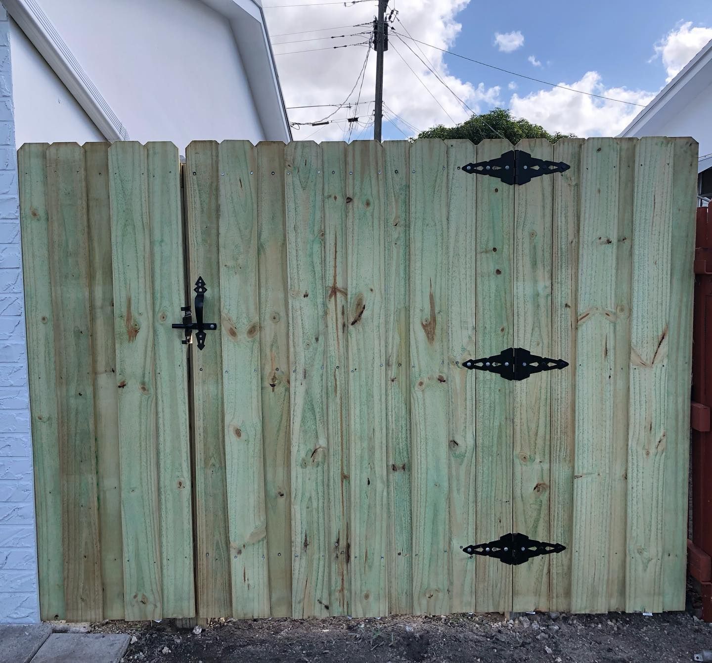 A green wooden fence with black hinges on it