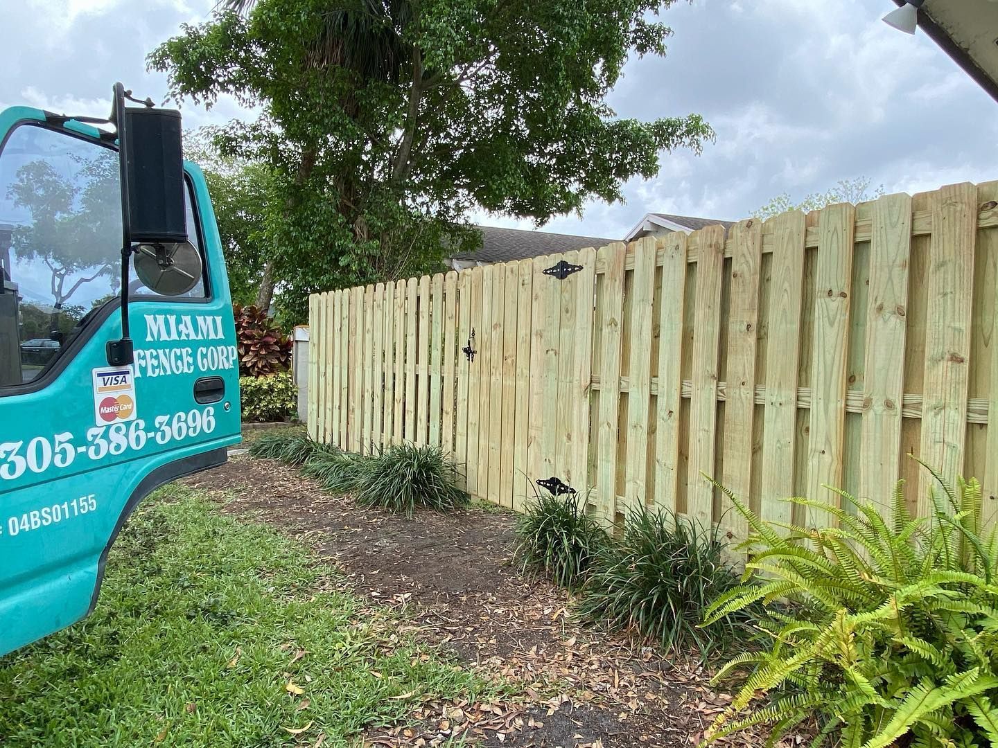 A blue truck is parked next to a wooden fence.