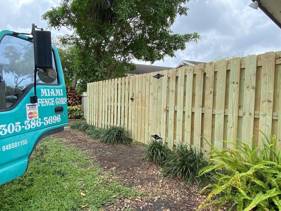 A blue truck is parked next to a wooden fence.