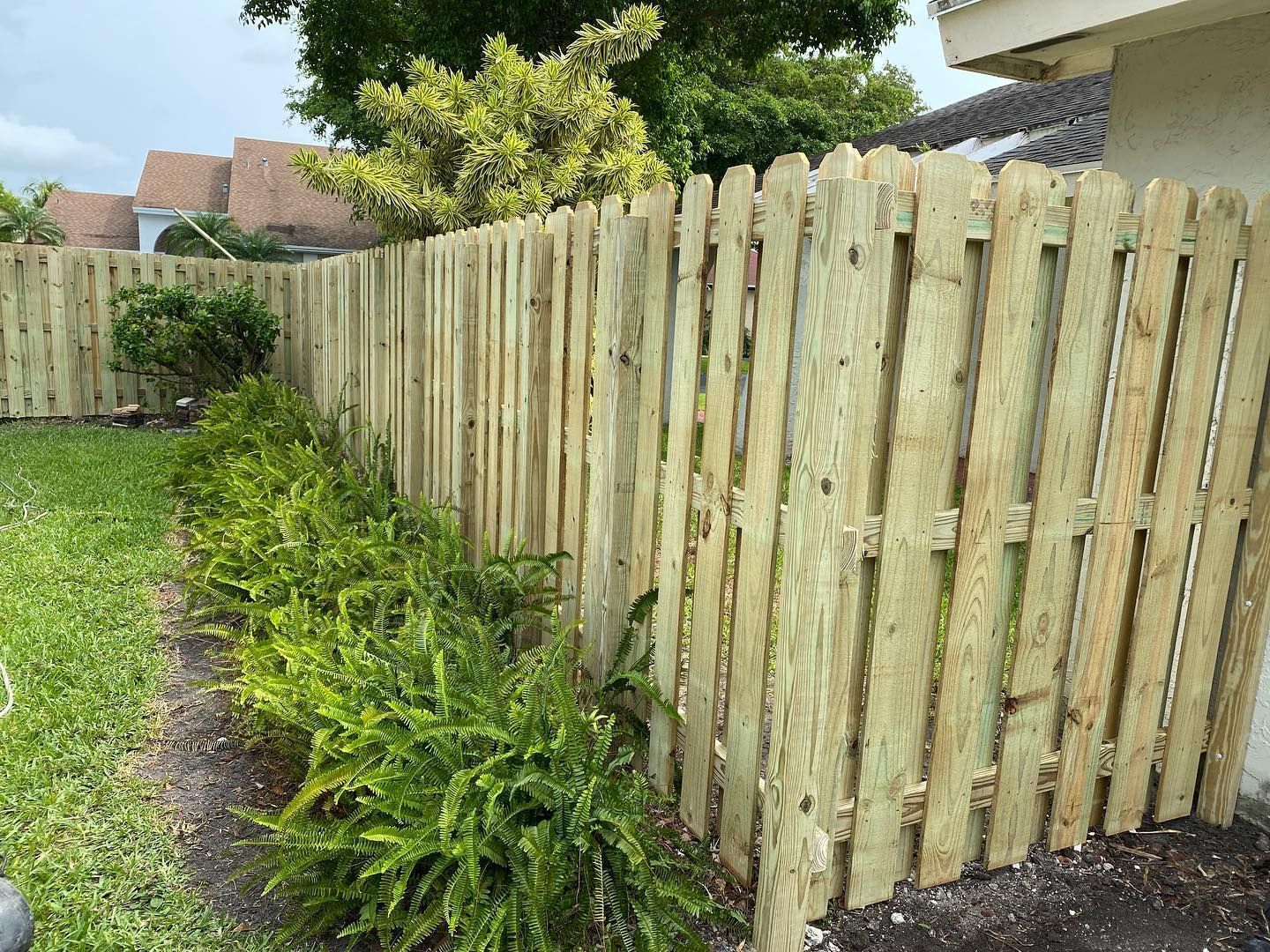 A wooden fence is in the backyard of a house.