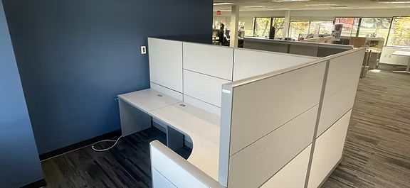 A cubicle with a desk and a chair in an office.